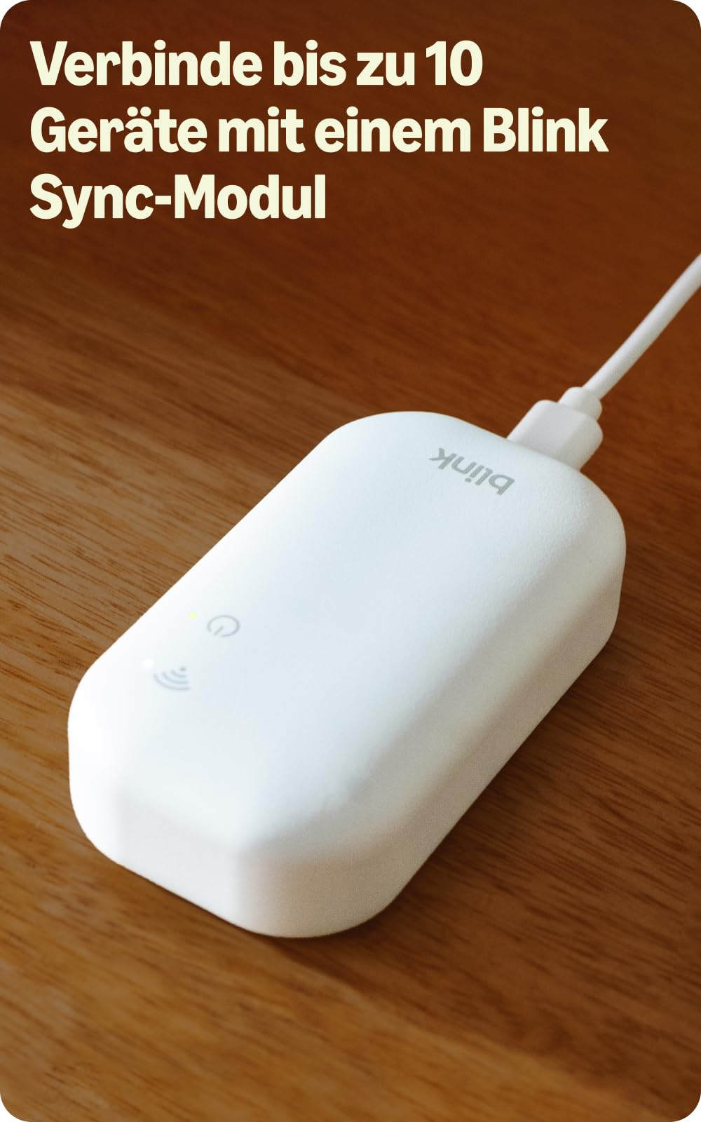 Un modulo Blink Sync bianco con cavo USB collegato si trova su una superficie di legno.