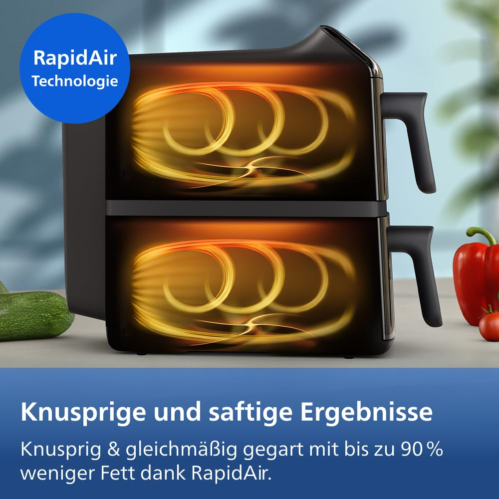 Friggitrice ad aria nera a doppio cestello con flussi di calore arancioni, su un piano di lavoro con verdure.