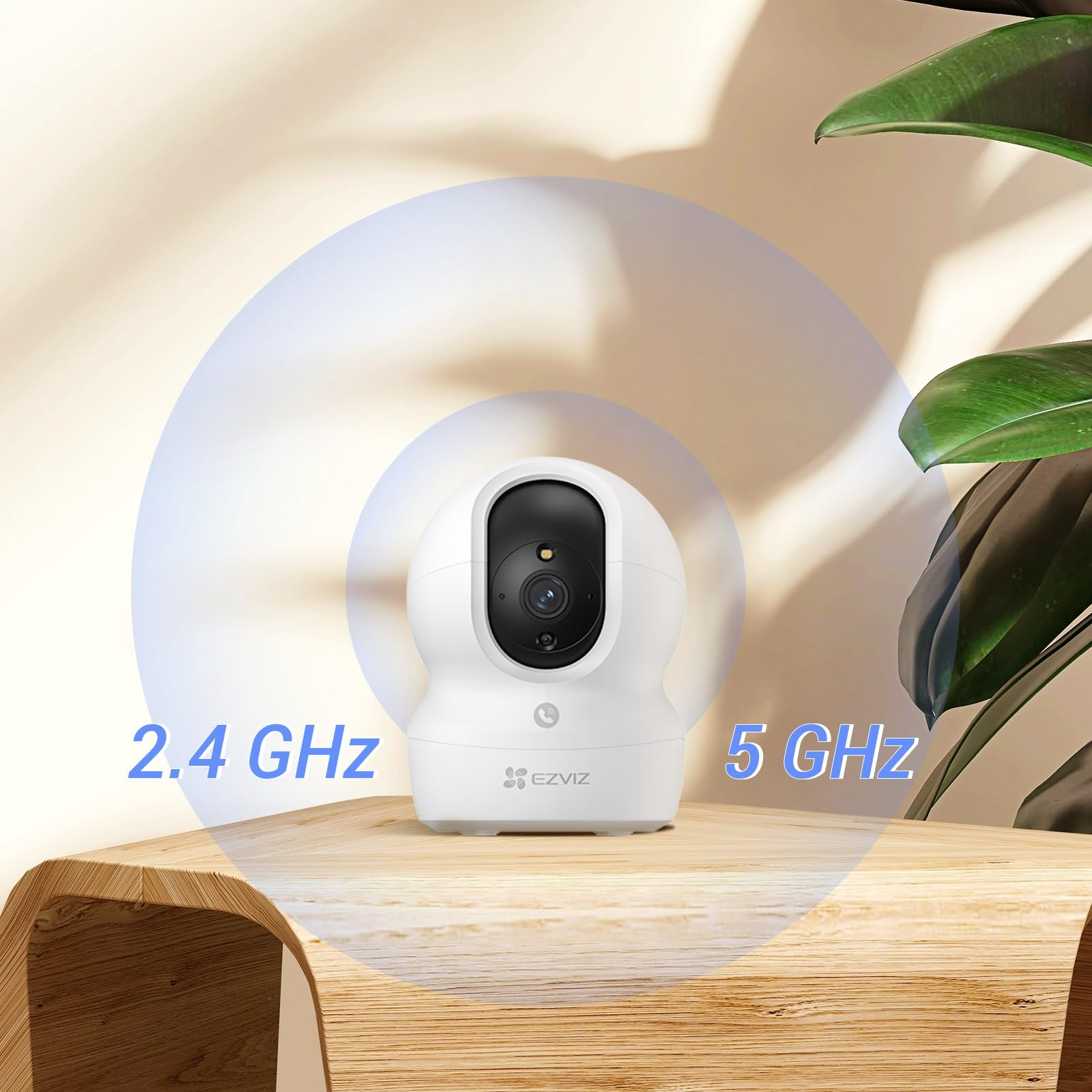 Une caméra de sécurité EZVIZ blanche sur une table en bois affiche des fréquences Wi-Fi de 2,4 GHz et 5 GHz.