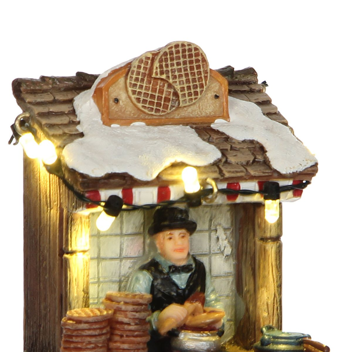 Stand de gaufres miniature d'hiver avec neige, enseigne de gaufres, lumières et vendeur.