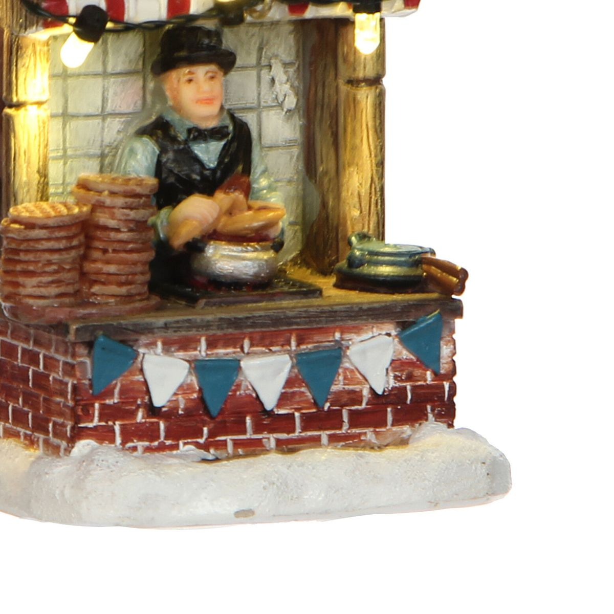 Une figurine miniature avec un chapeau et un gilet vend des gaufres dans un stand festif décoré de neige.
