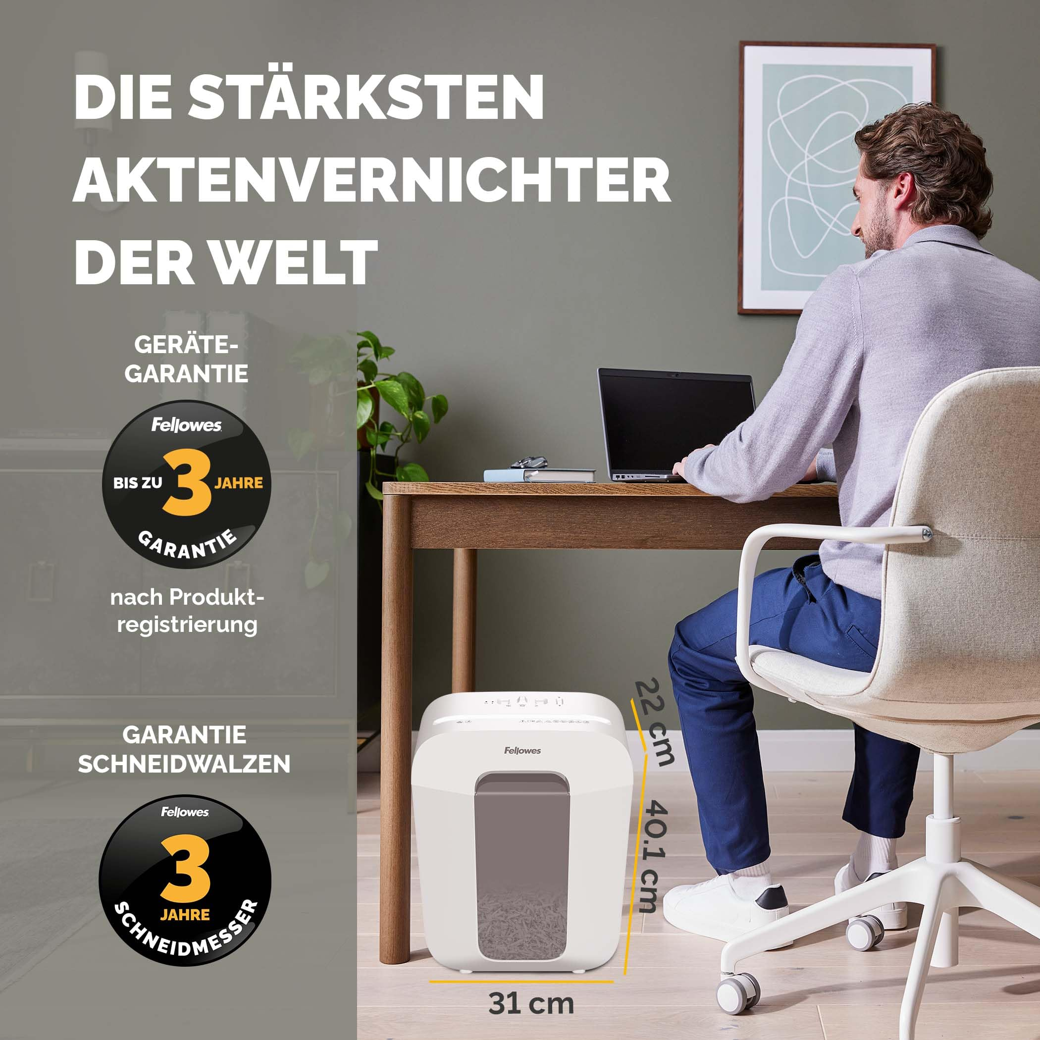Ein Mann sitzt an einem Holztisch mit Laptop, davor steht ein weißer Fellowes Aktenvernichter.