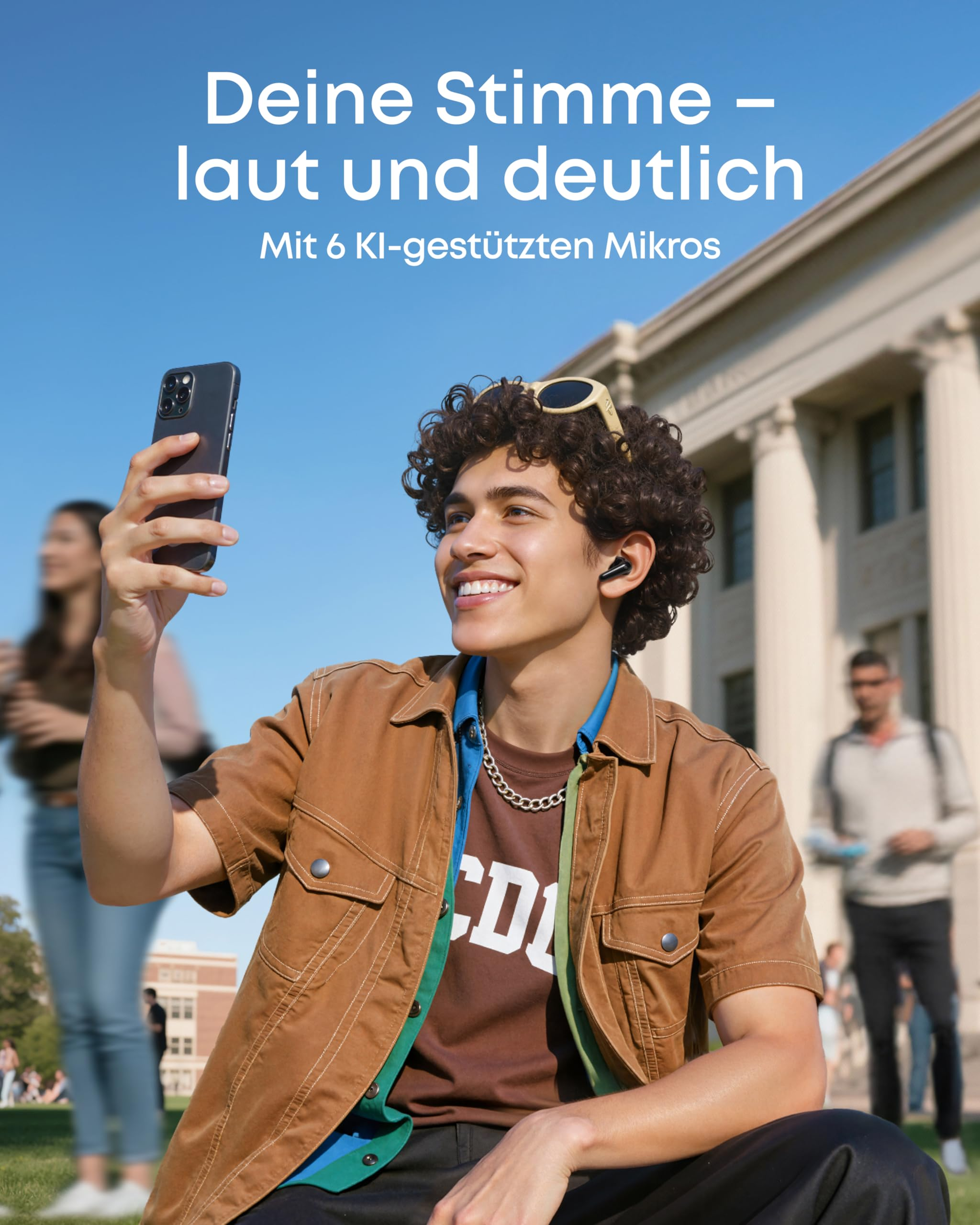 Un jeune homme avec des lunettes sur la tête prend un selfie avec son smartphone en extérieur.
