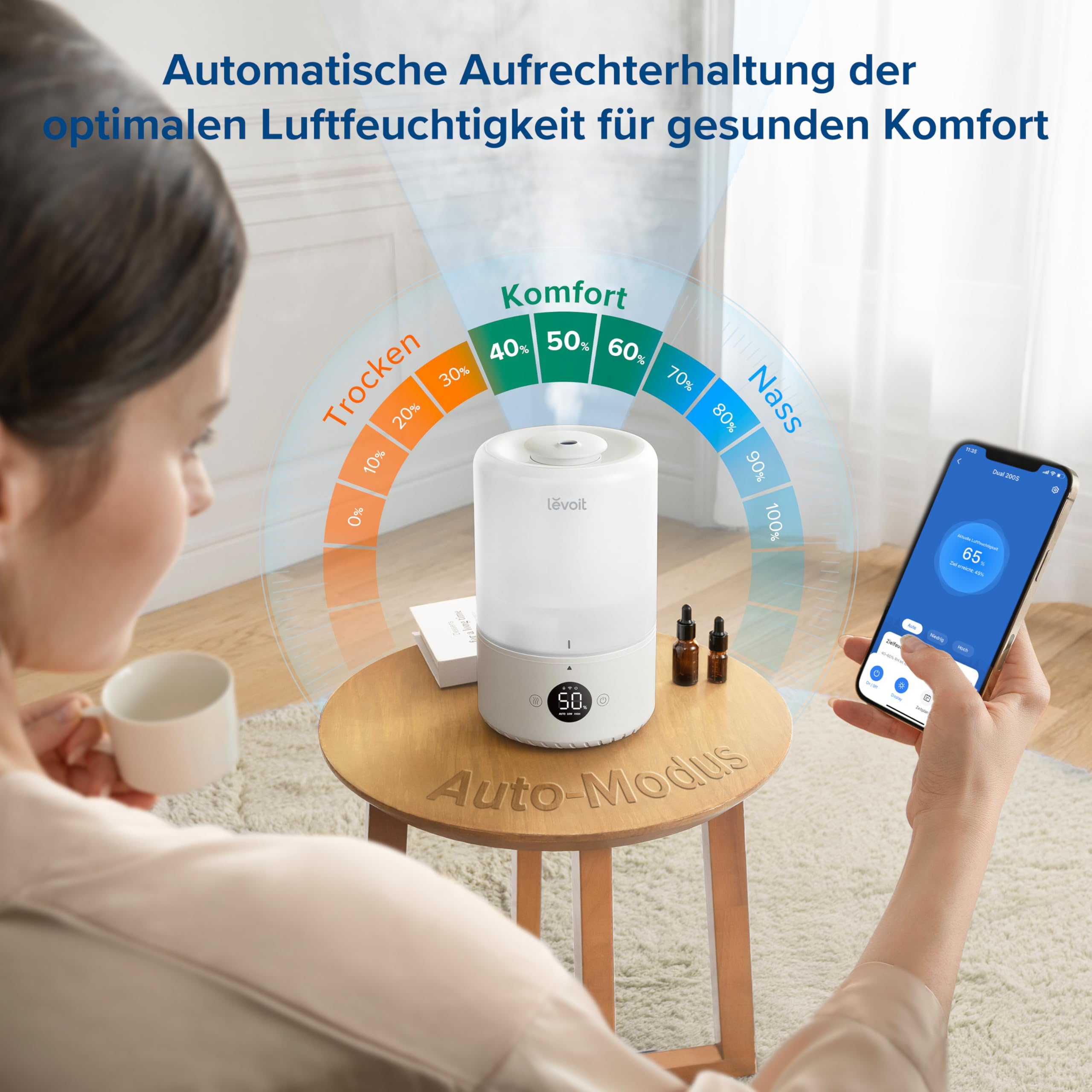 Una donna tiene in mano uno smartphone che controlla un umidificatore bianco.