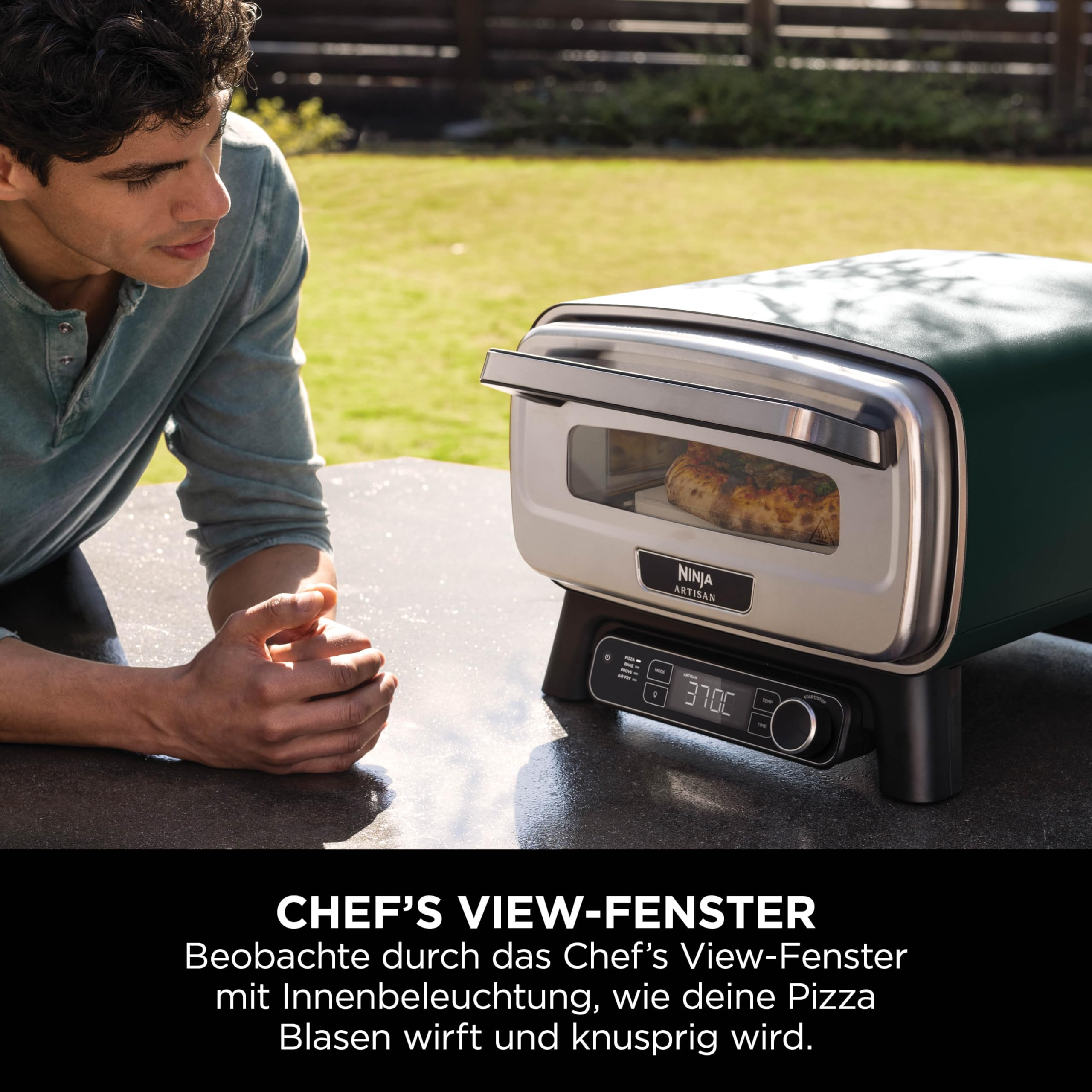 Un homme regarde un four à pizza Ninja vert sur une table extérieure, cuisant une pizza.