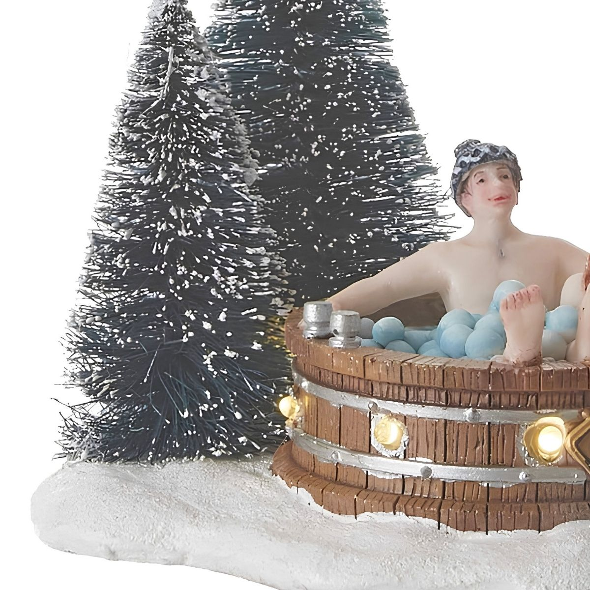 Figurine d'une personne dans un bain à remous en bois avec bulles bleues, près de sapins enneigés.