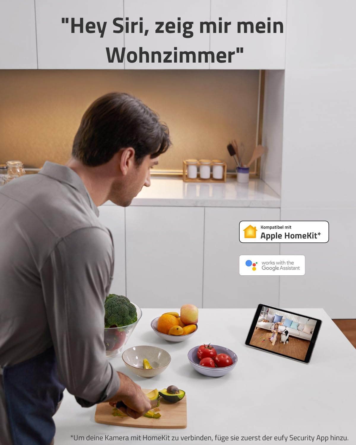 Un uomo prepara frutta in una cucina moderna mentre un tablet mostra una telecamera in diretta.