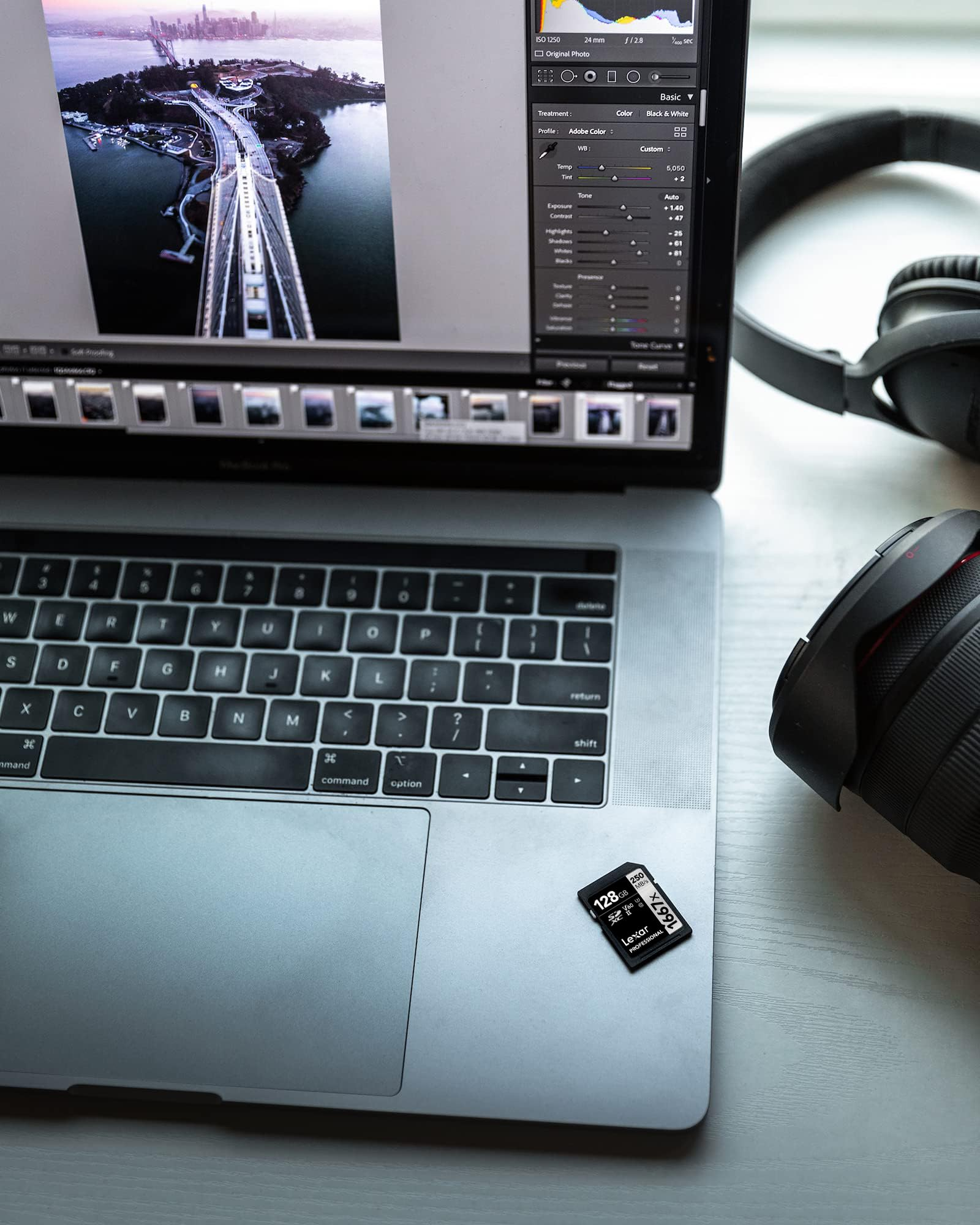Ordinateur portable affichant un logiciel de retouche, une carte mémoire et un casque.