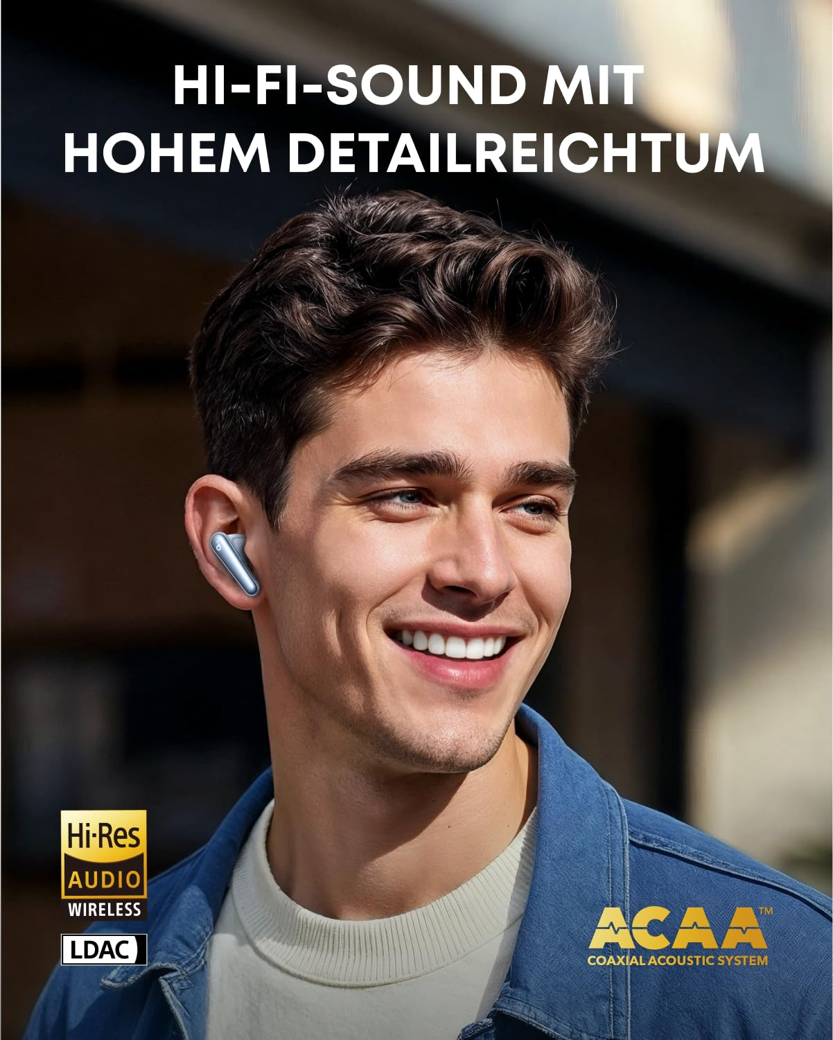 Un uomo sorridente che indossa auricolari blu e una giacca blu su sfondo sfocato.