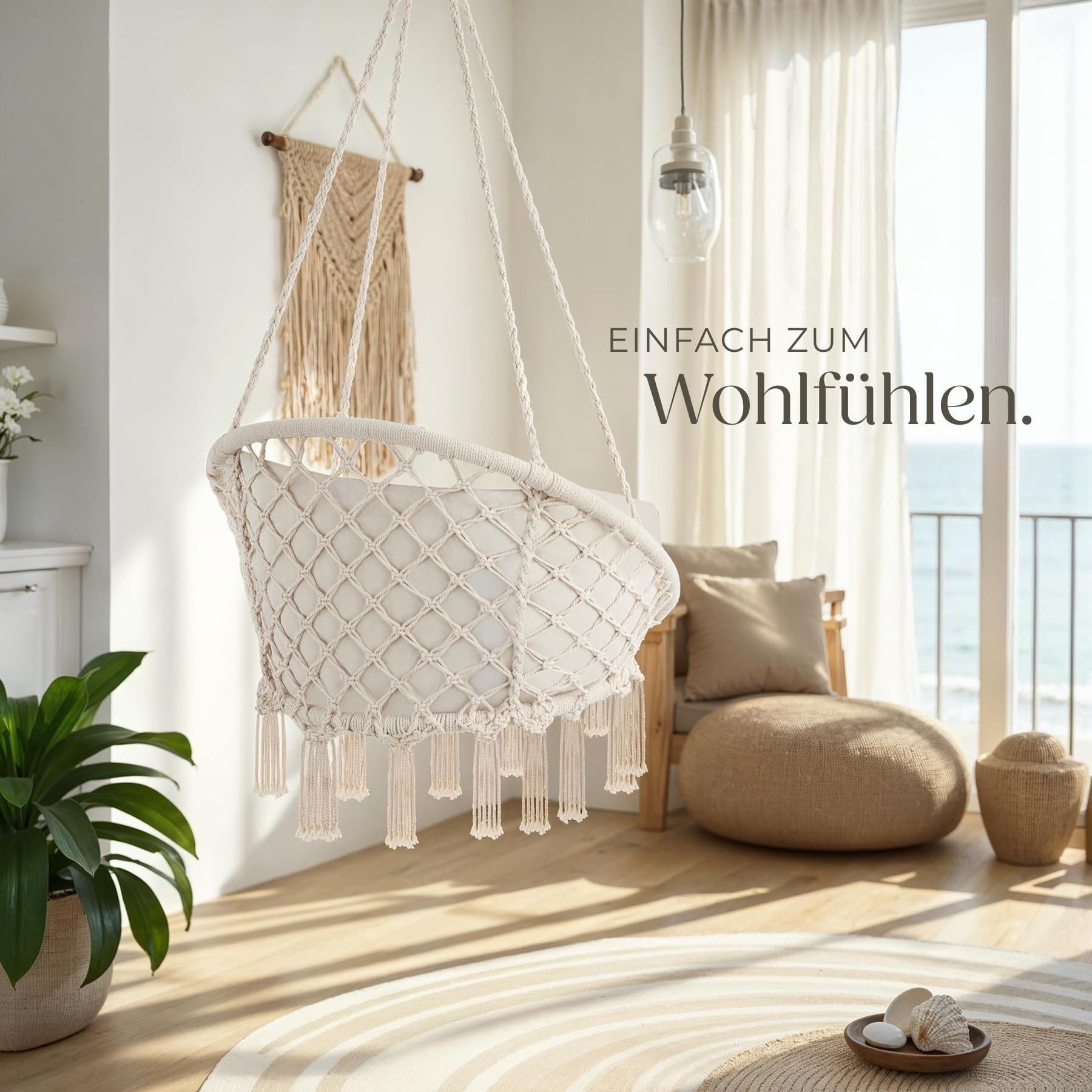 Ein beiger Hängesessel aus Makramee in einem hellen Wohnzimmer mit Meerblick und Text 'Einfach zum Wohlfühlen'.