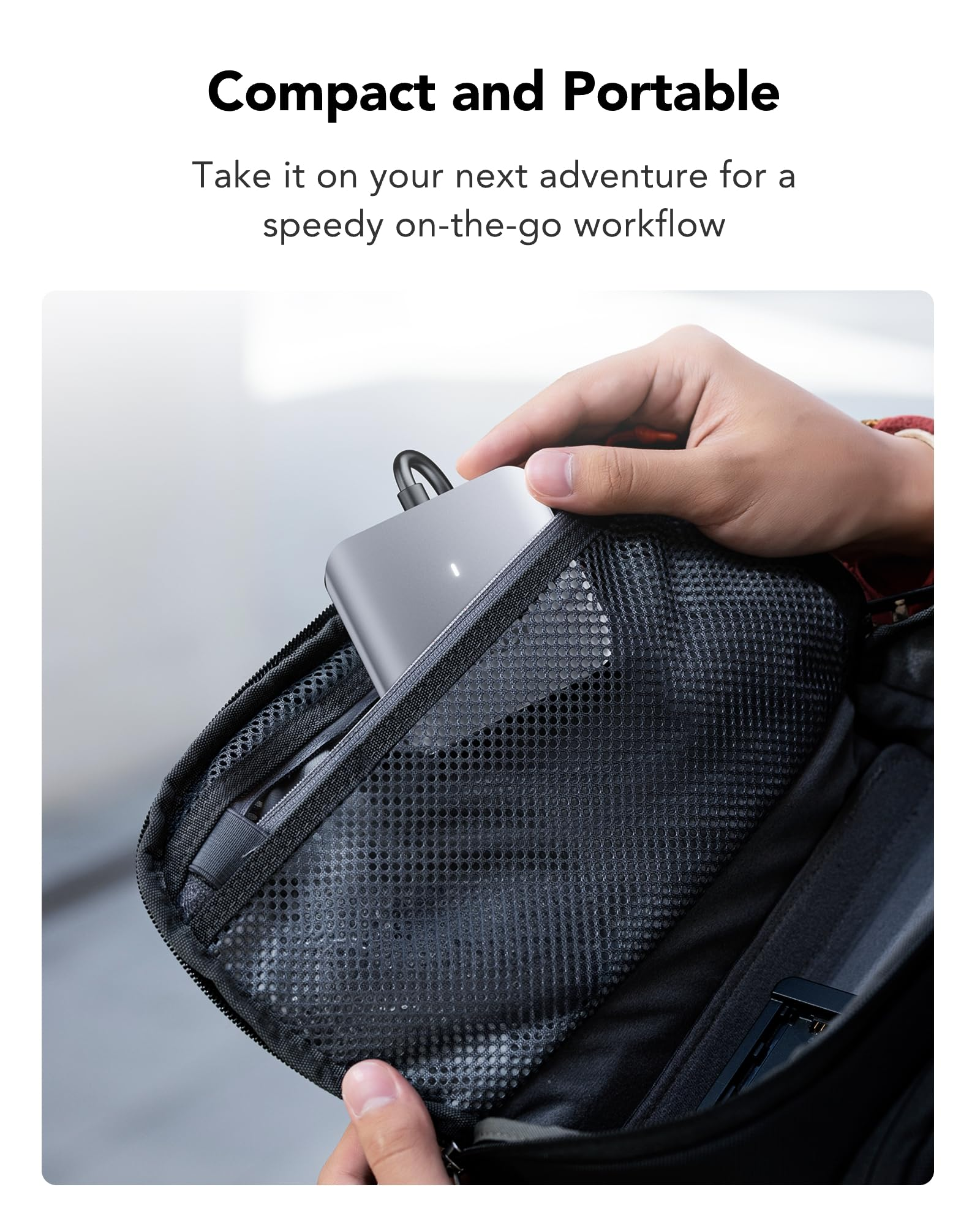 Eine Hand verstaut ein graues elektronisches Gerät in einer schwarzen Mesh-Tasche eines Rucksacks.