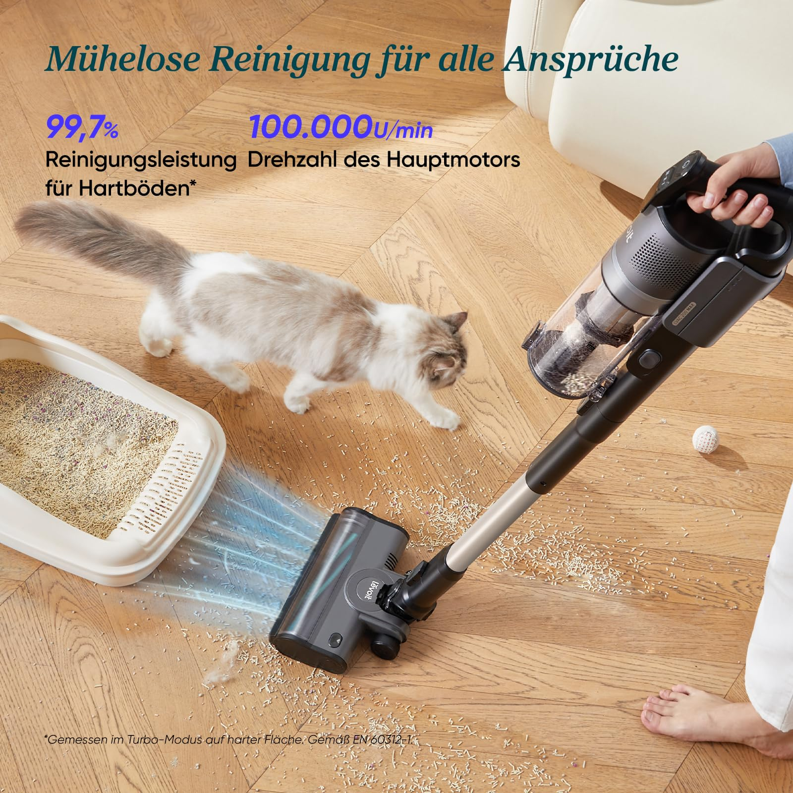 Un aspirapolvere senza fili pulisce la sabbia per gatti dai pavimenti in legno mentre un gatto cammina.
