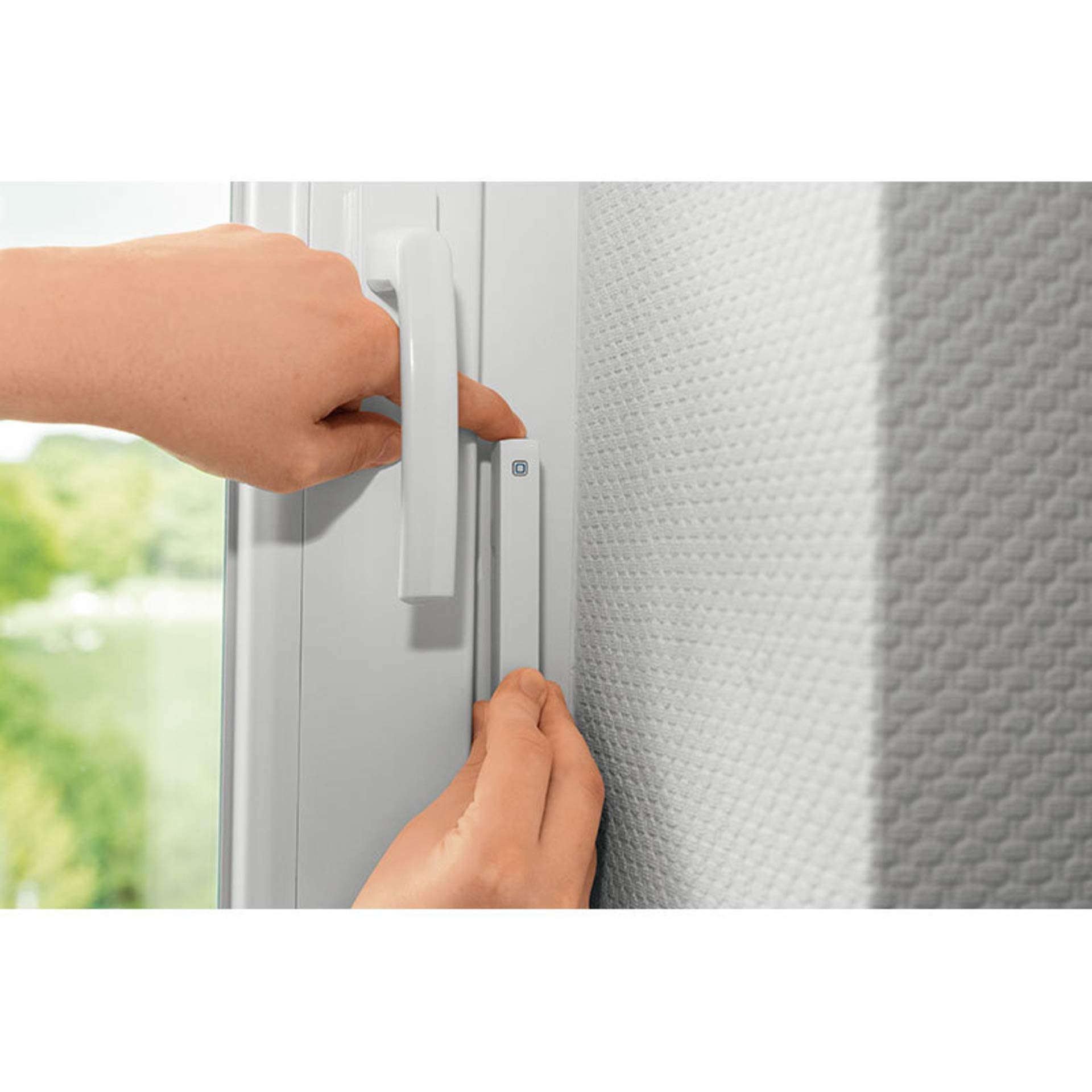 Hände installieren einen weißen Smart-Sensor an einem Fensterrahmen neben dem Griff.