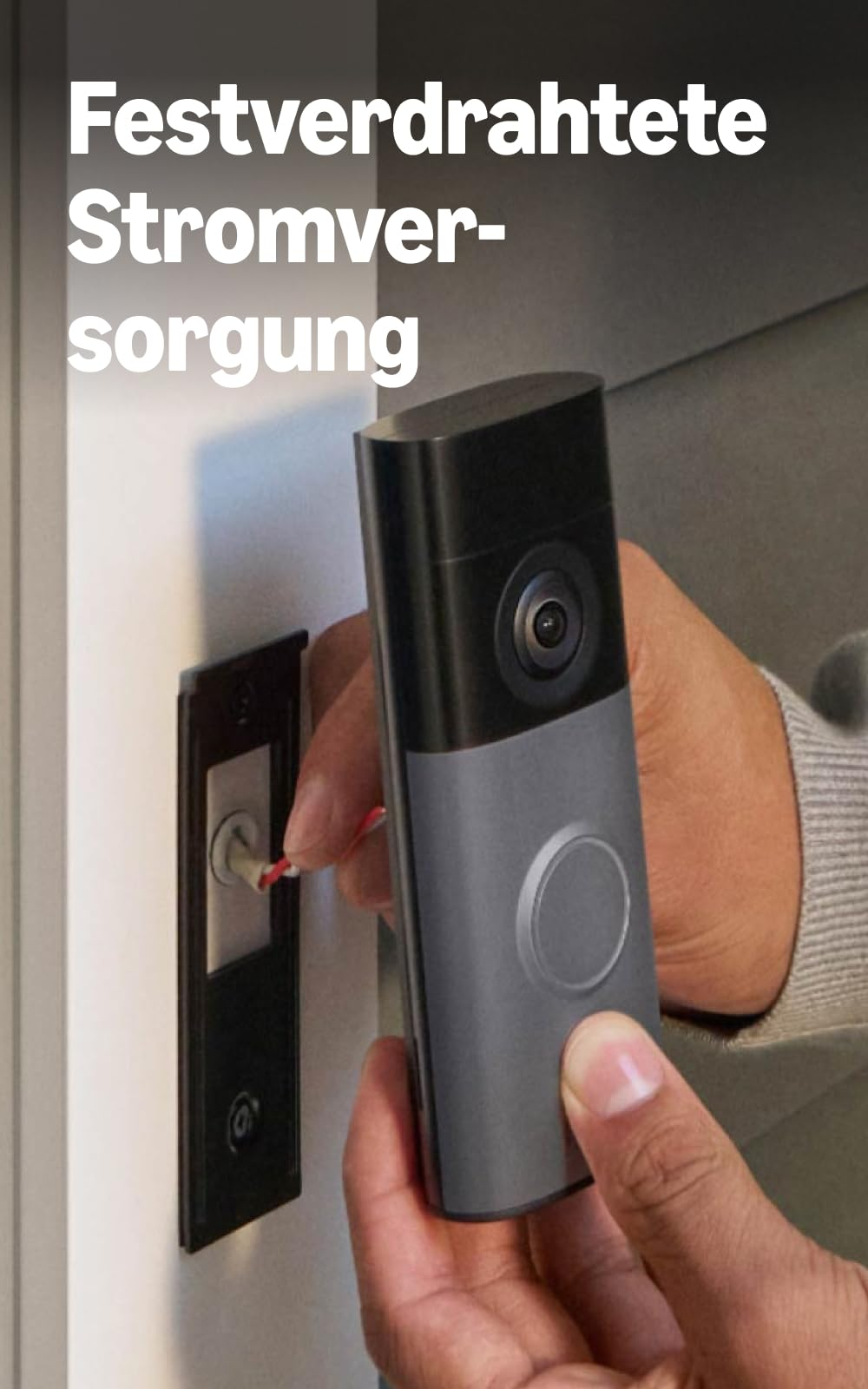 Person installiert eine Videoklingel an einer Hauswand und verbindet Kabel.
