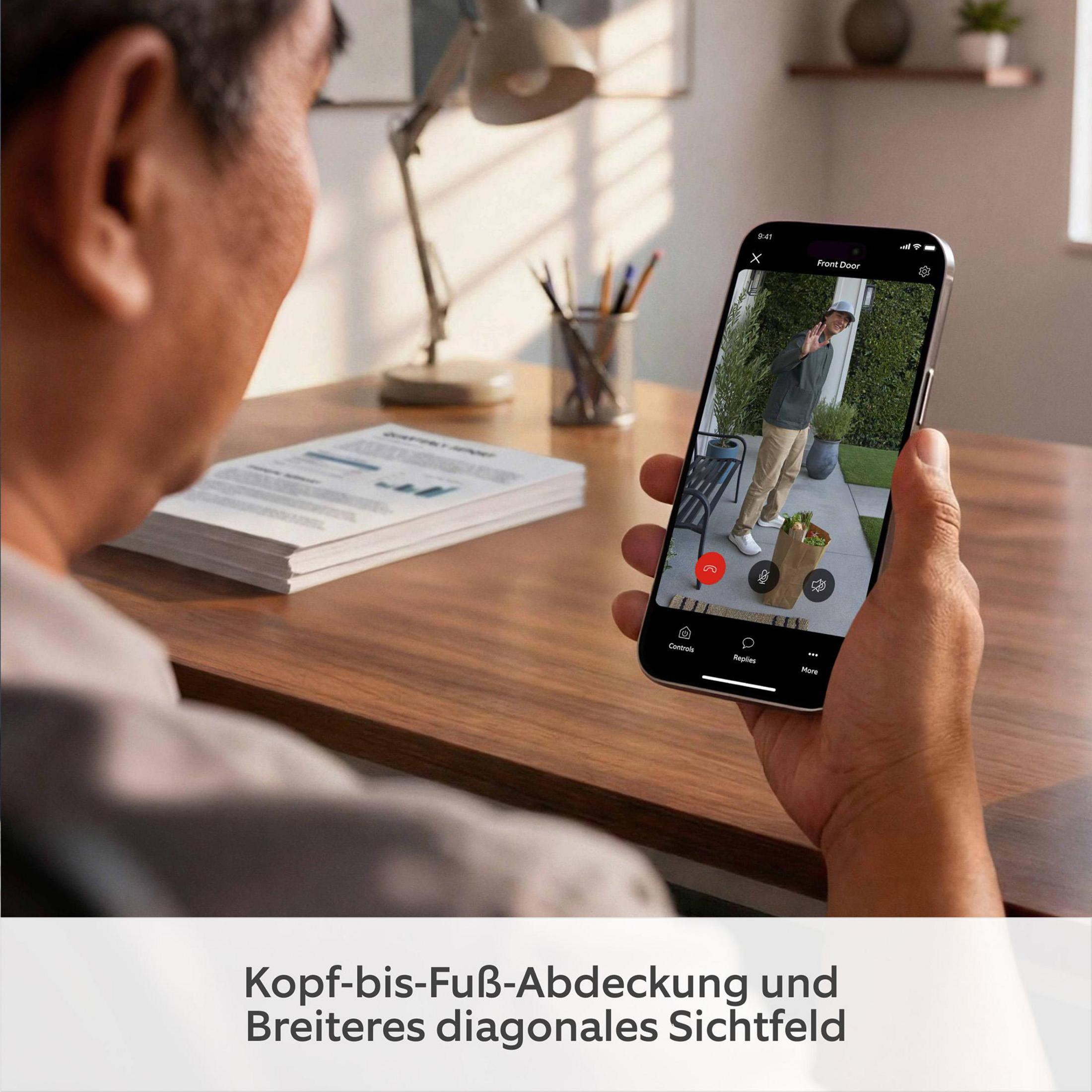 Eine Person hält ein Smartphone mit einem Haustür-Videoanruf und einem winkenden Besucher.