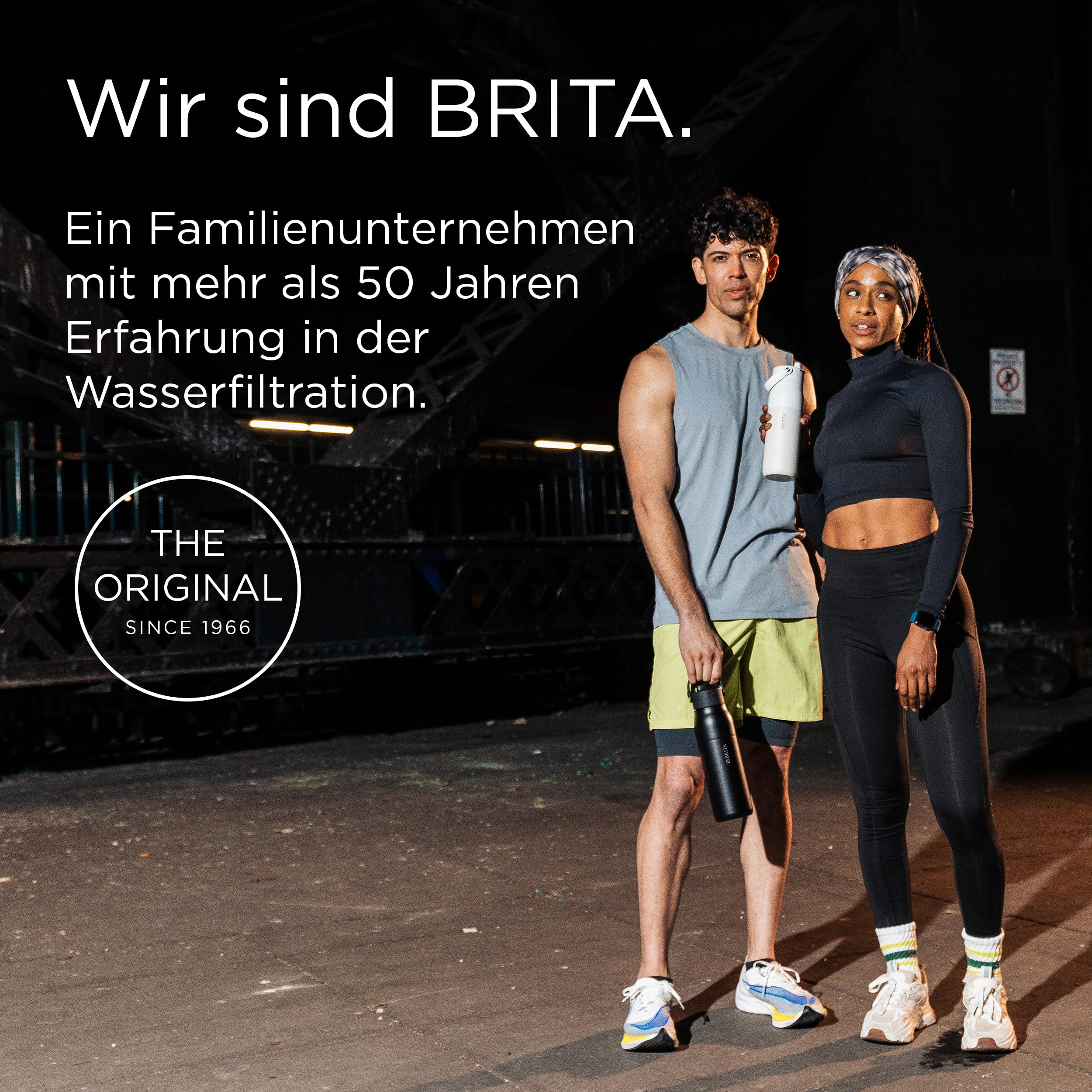 Zwei sportliche Personen mit Wasserflaschen stehen nachts vor einer urbanen Brücke, mit deutschem Werbetext.