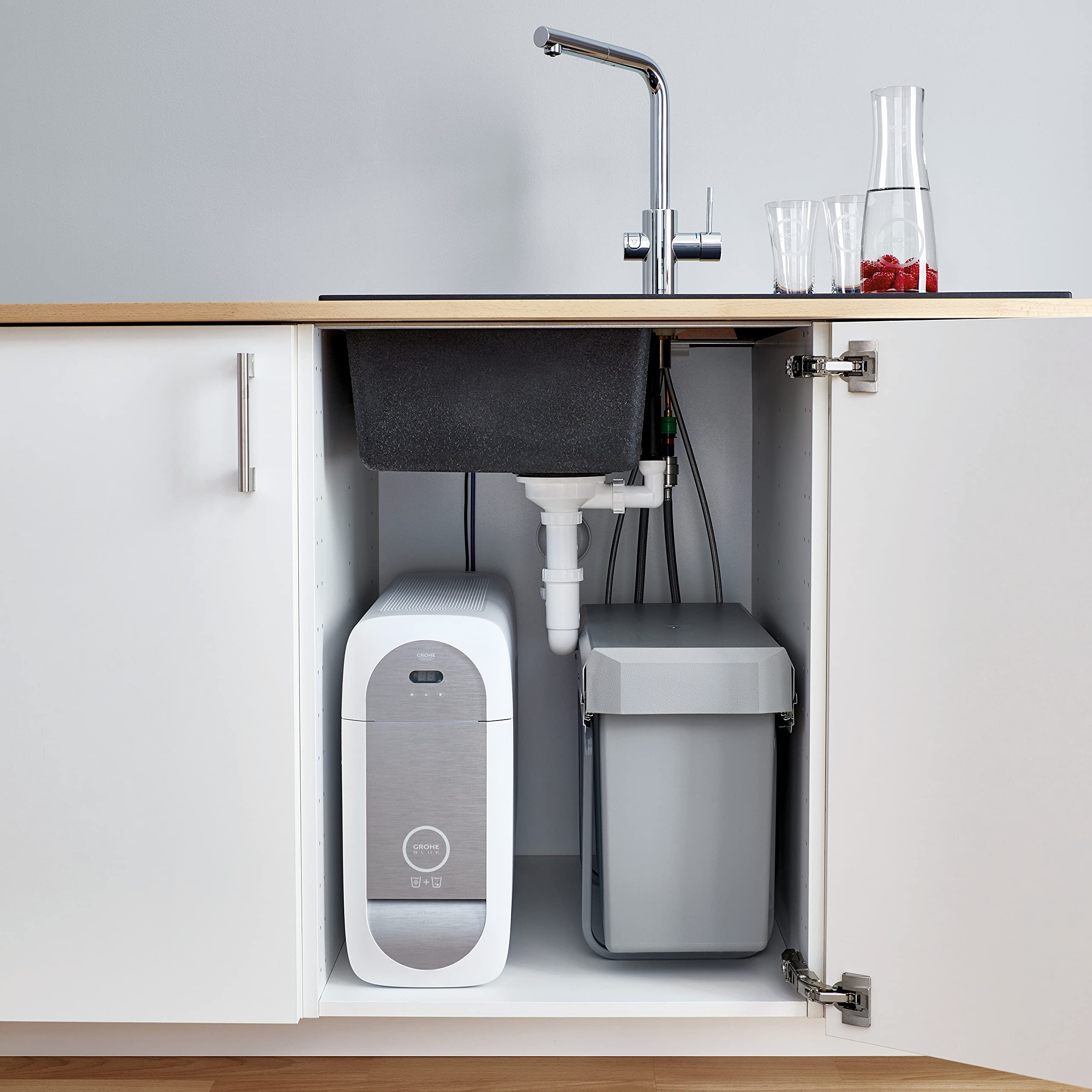 Offener Küchenschrank zeigt ein Grohe-Filtersystem und einen Mülleimer unter dem Spülbecken.