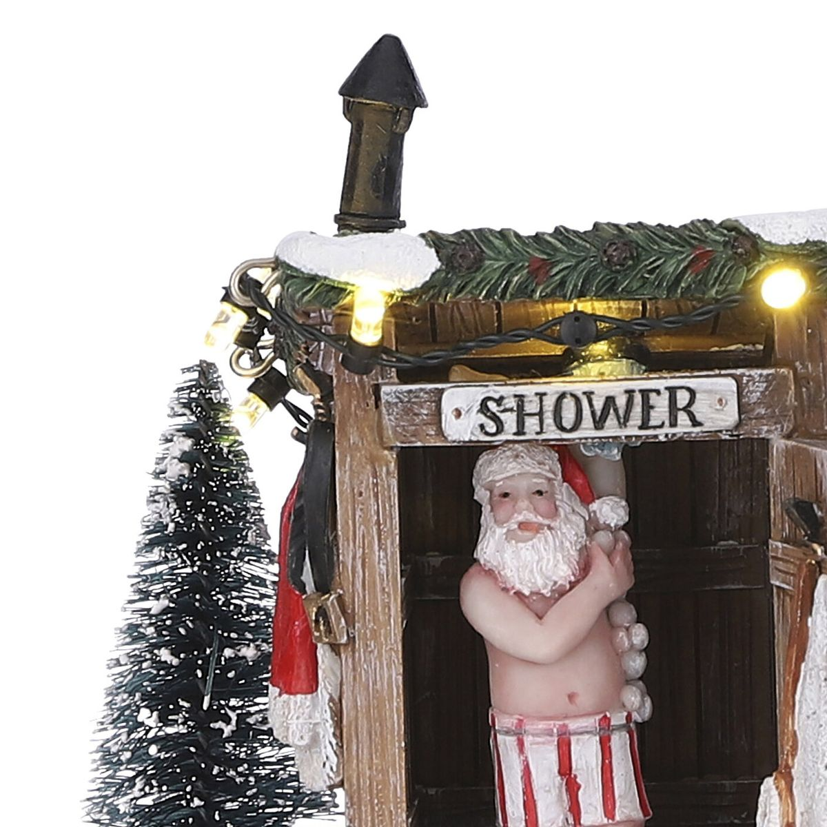 Santa figure in a rustic shower stall with a sign, Christmas lights, and a snowy pine tree nearby.