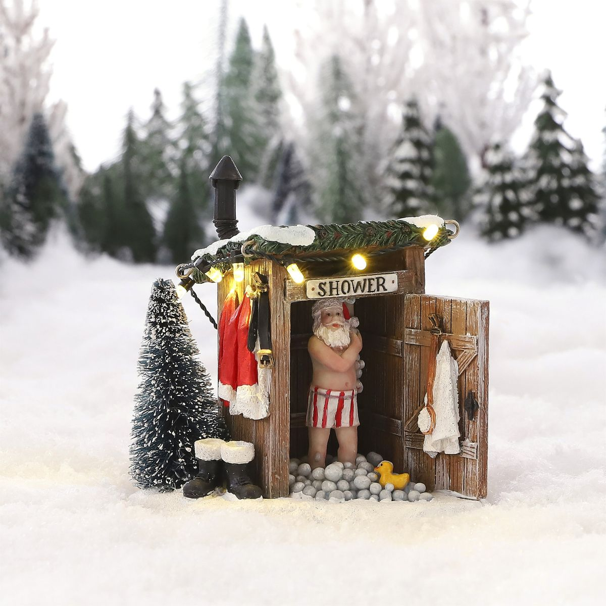 A Santa figurine showering in a wooden shed in the snow, surrounded by snow-covered fir trees.