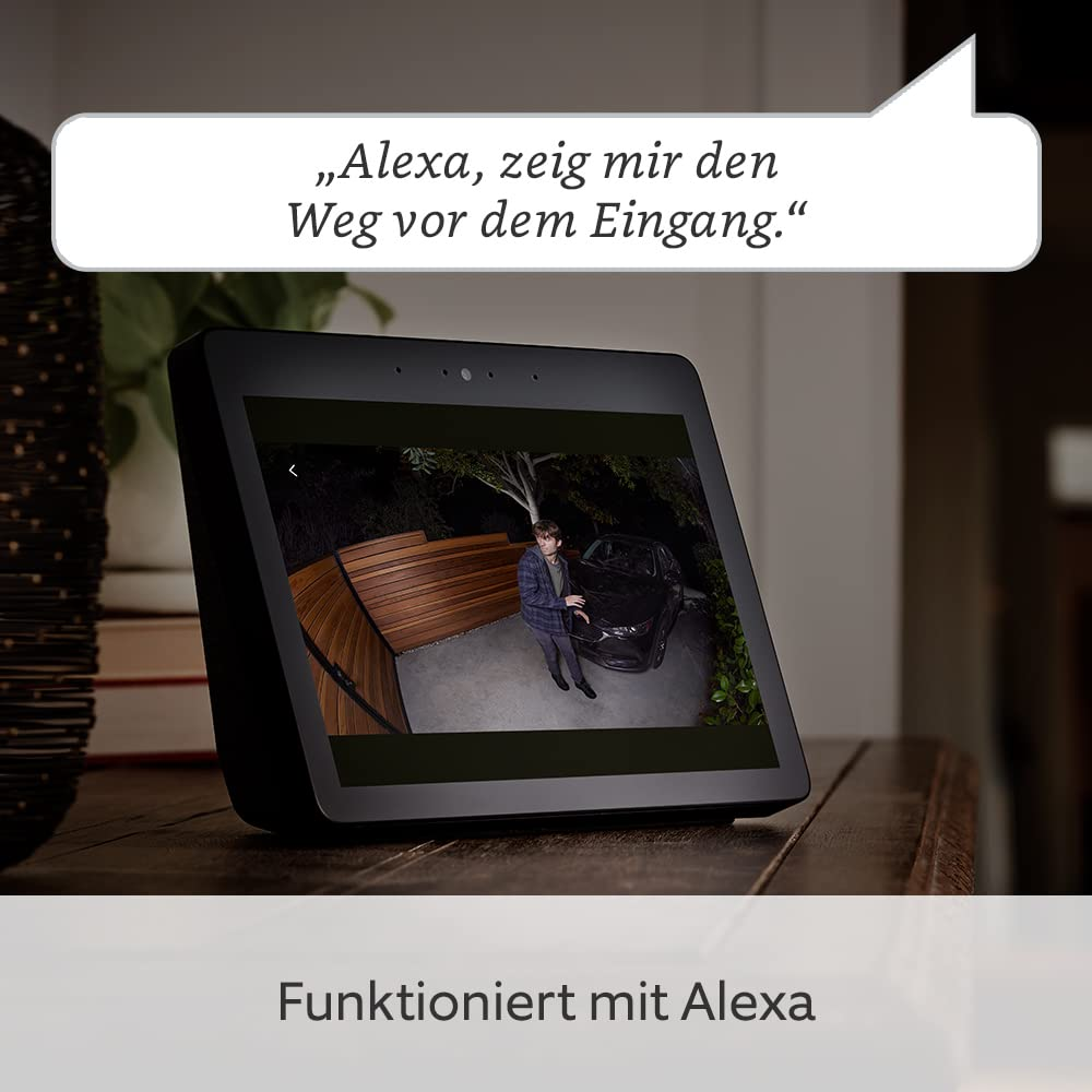 Un Echo Show mostra la telecamera esterna di un uomo in piedi in un vialetto vicino a un'auto.