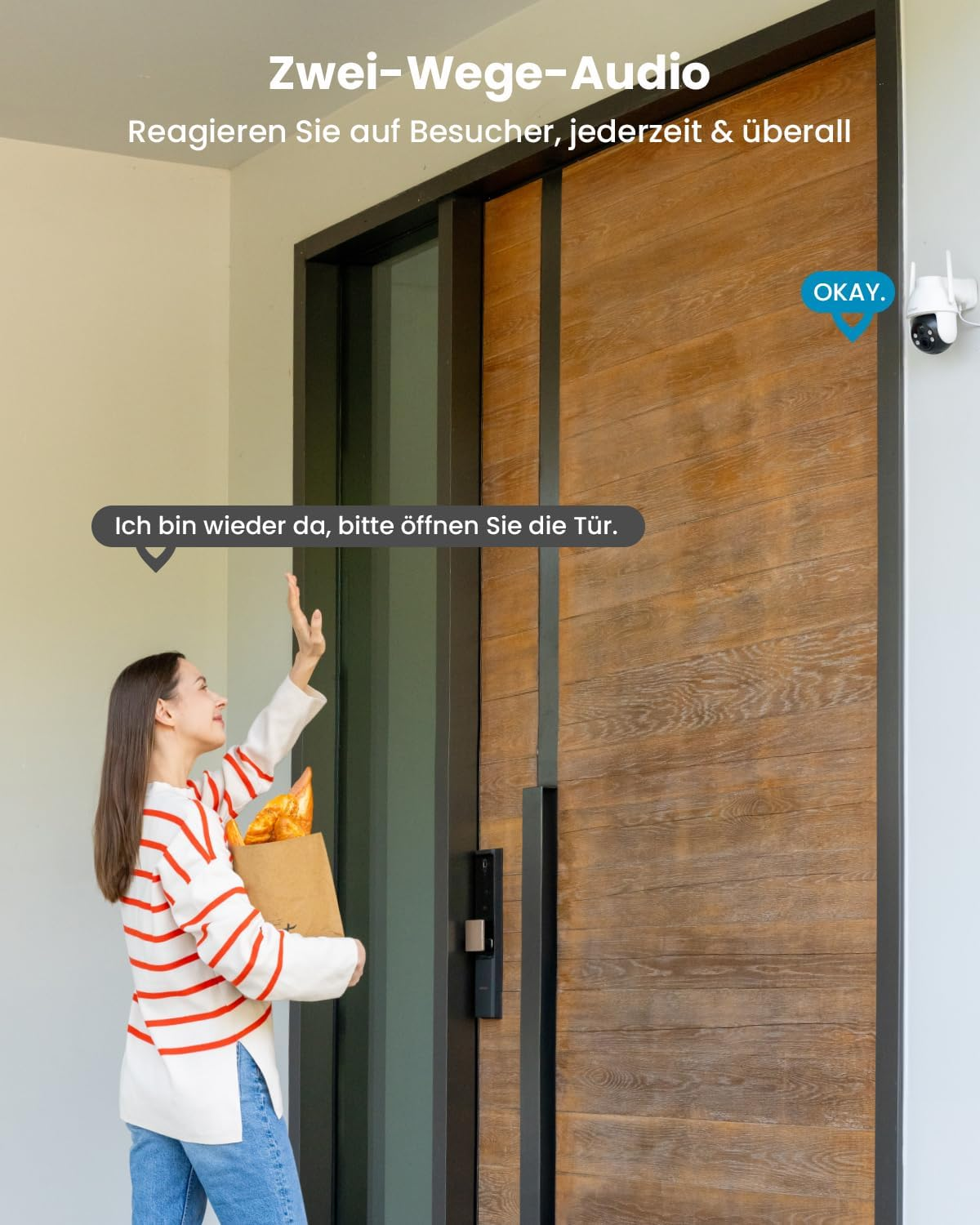 Una donna con la spesa saluta una porta in legno con telecamera.