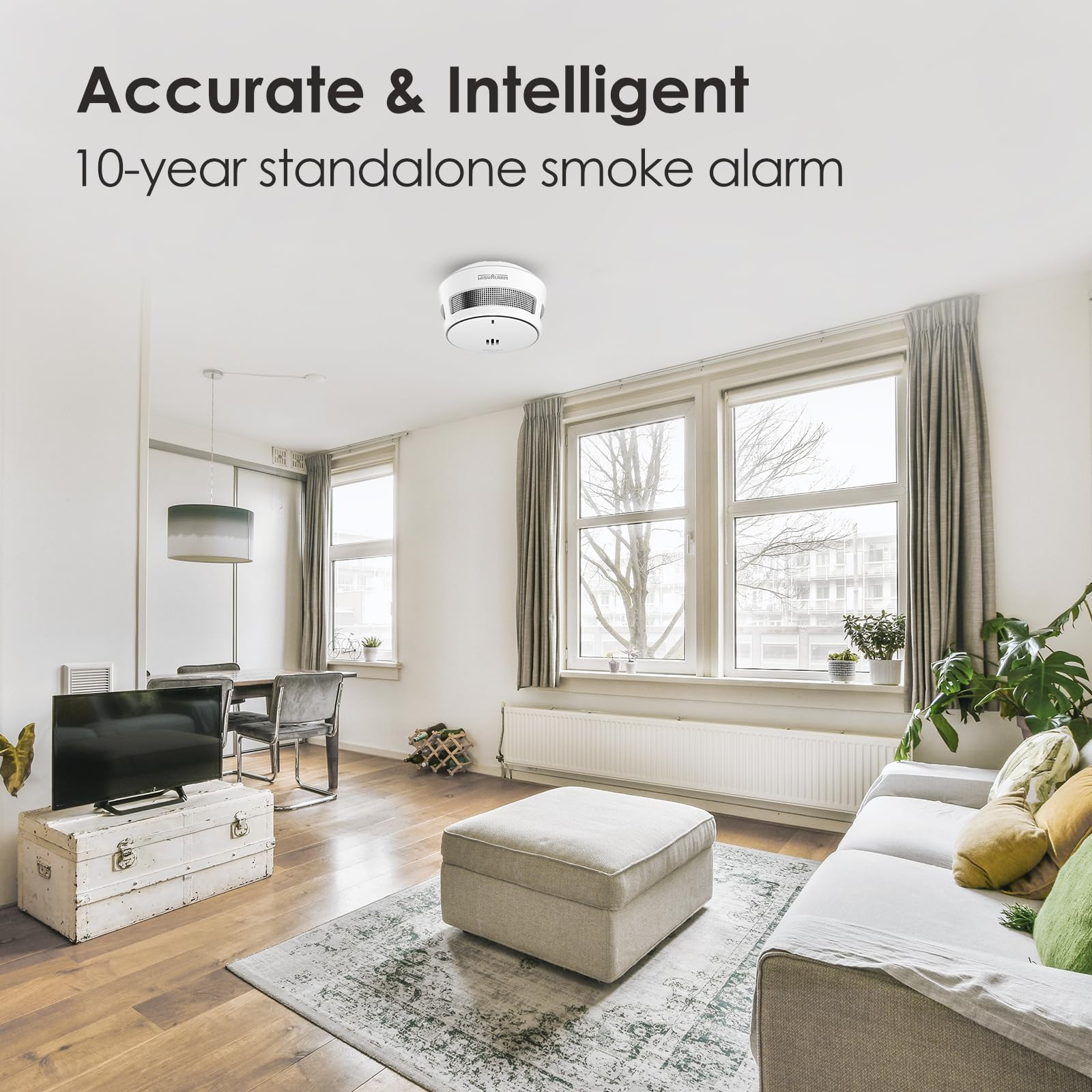 Ein weißer Rauchmelder hängt an der Decke eines modernen, hellen Wohnzimmers mit Sofa, Tisch und Fenstern.