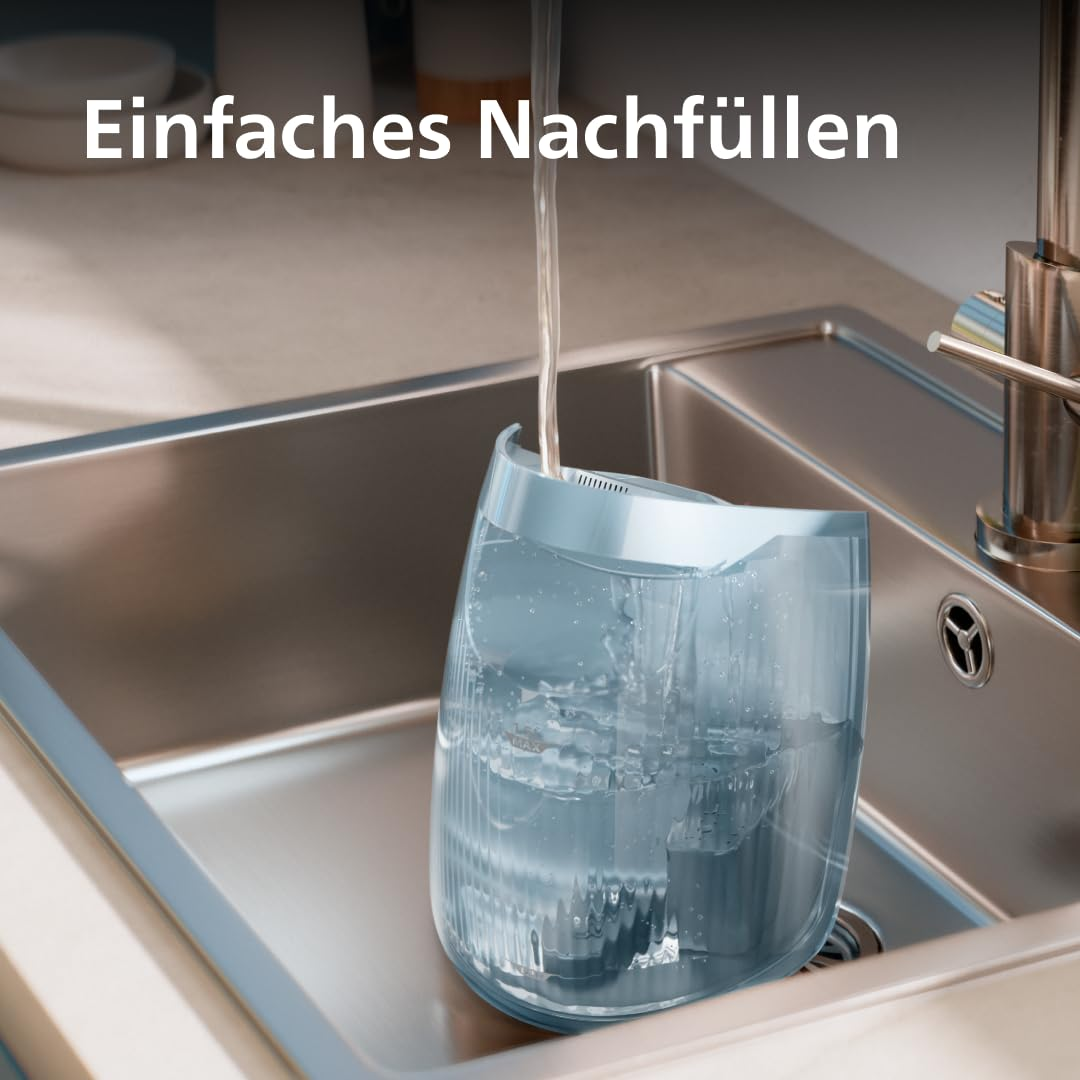 Wasser läuft aus einem modernen Küchenwasserhahn in einen blauen Wassertank im Edelstahlspülbecken.