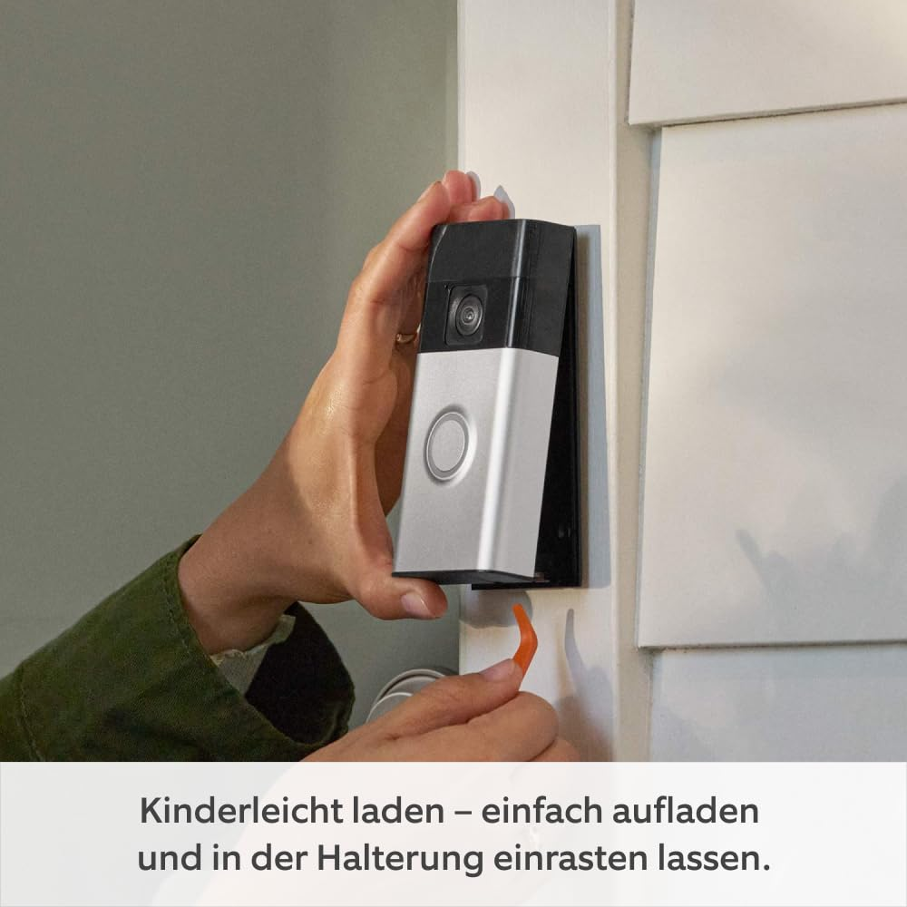 Eine Person montiert eine Video-Türklingel an einer Wandhalterung, mit deutschem Text unten.