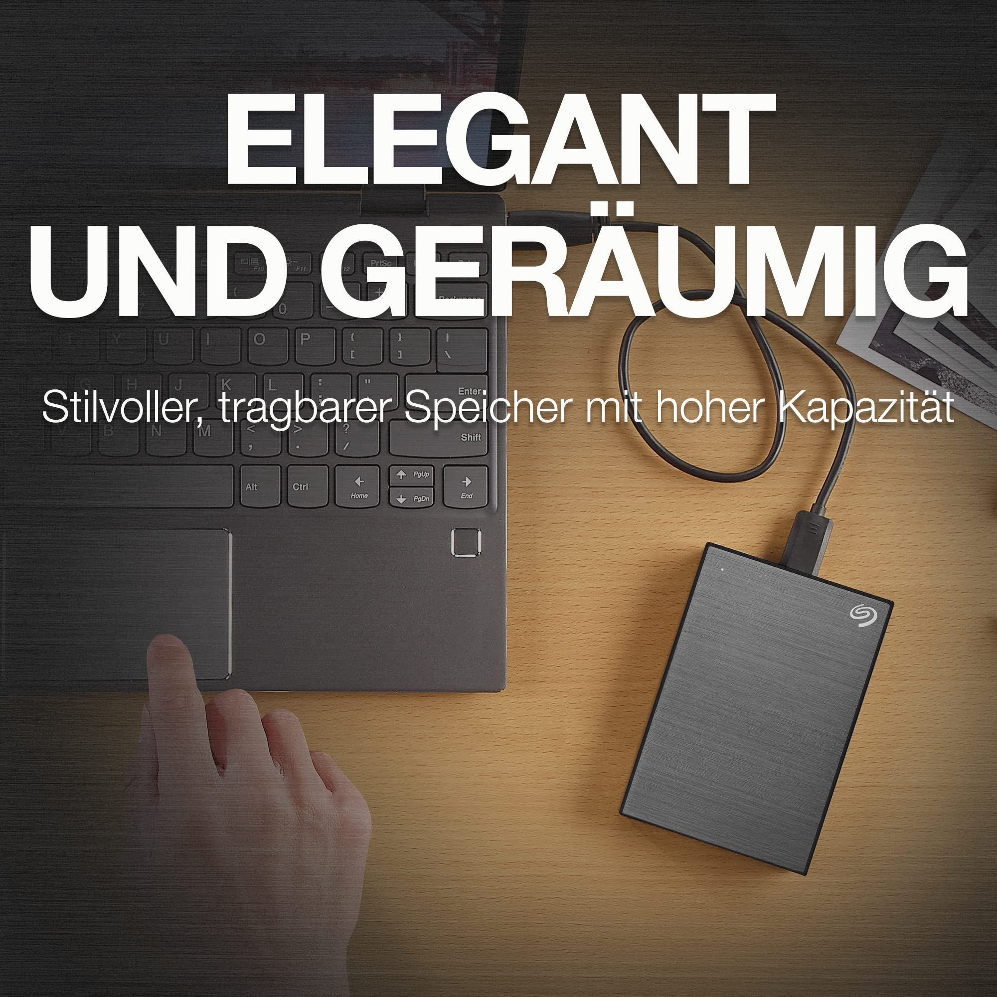 Eine externe Festplatte ist per Kabel mit einem Laptop verbunden, während eine Hand auf dem Trackpad ruht.
