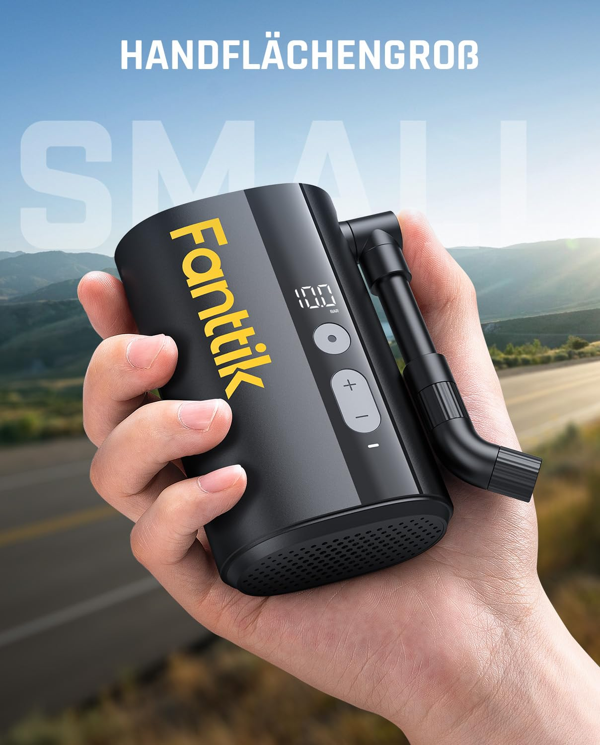 Une main tient un compresseur d'air Fanttik noir compact devant un paysage de montagnes.
