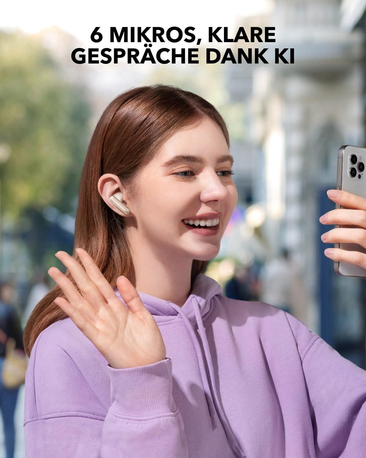 Une femme souriante portant des écouteurs fait signe à son smartphone dans la rue.