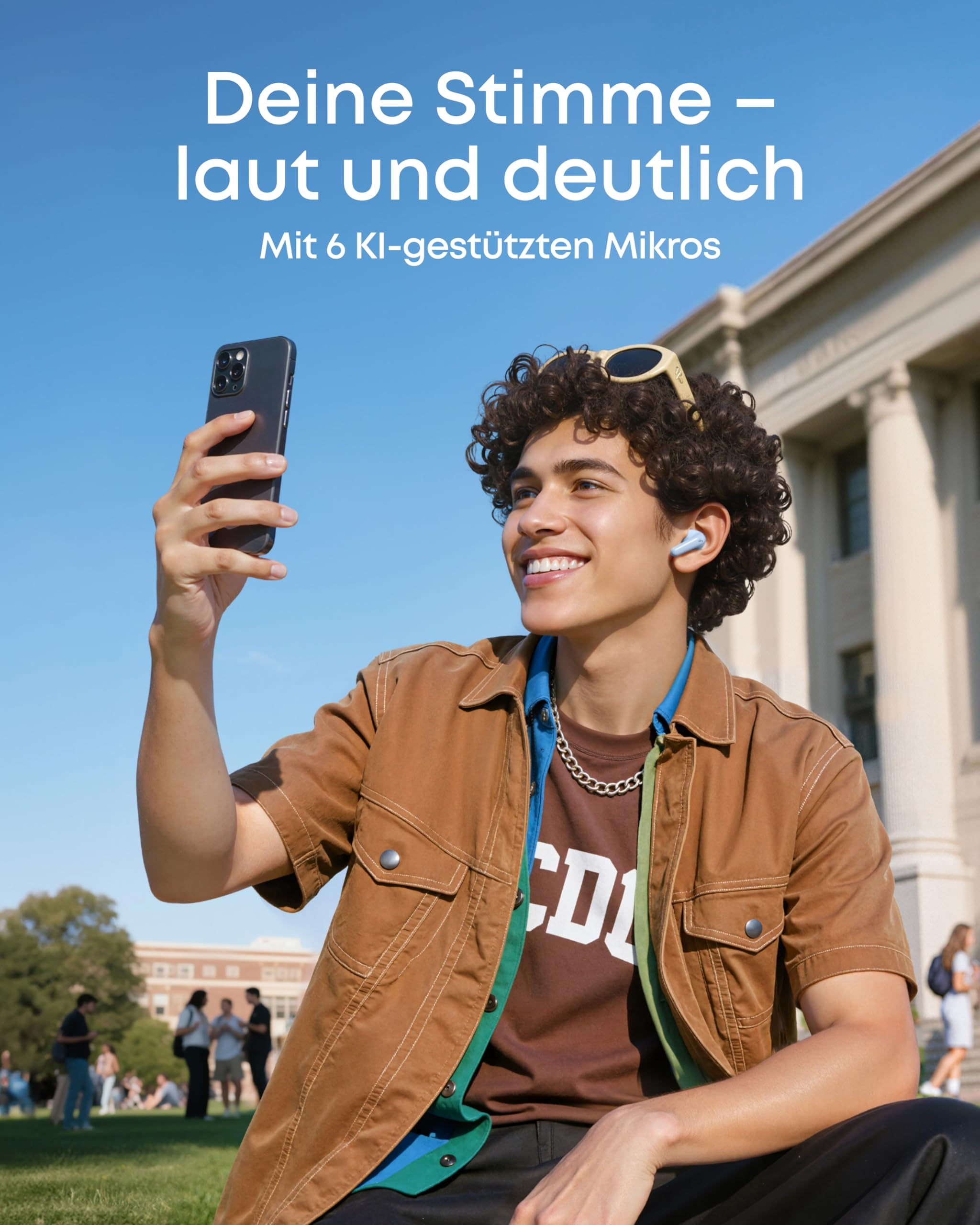 Jeune homme avec des écouteurs tenant un smartphone avec un bâtiment et un ciel bleu en arrière-plan.