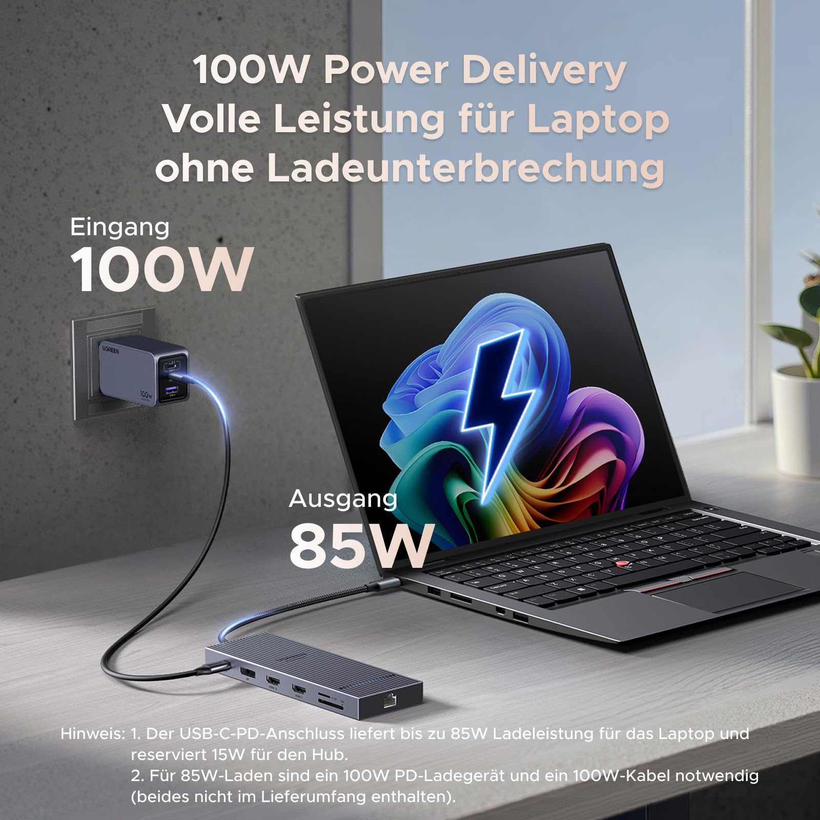 Un caricatore a muro da 100W alimenta un computer portatile su una scrivania tramite un hub.