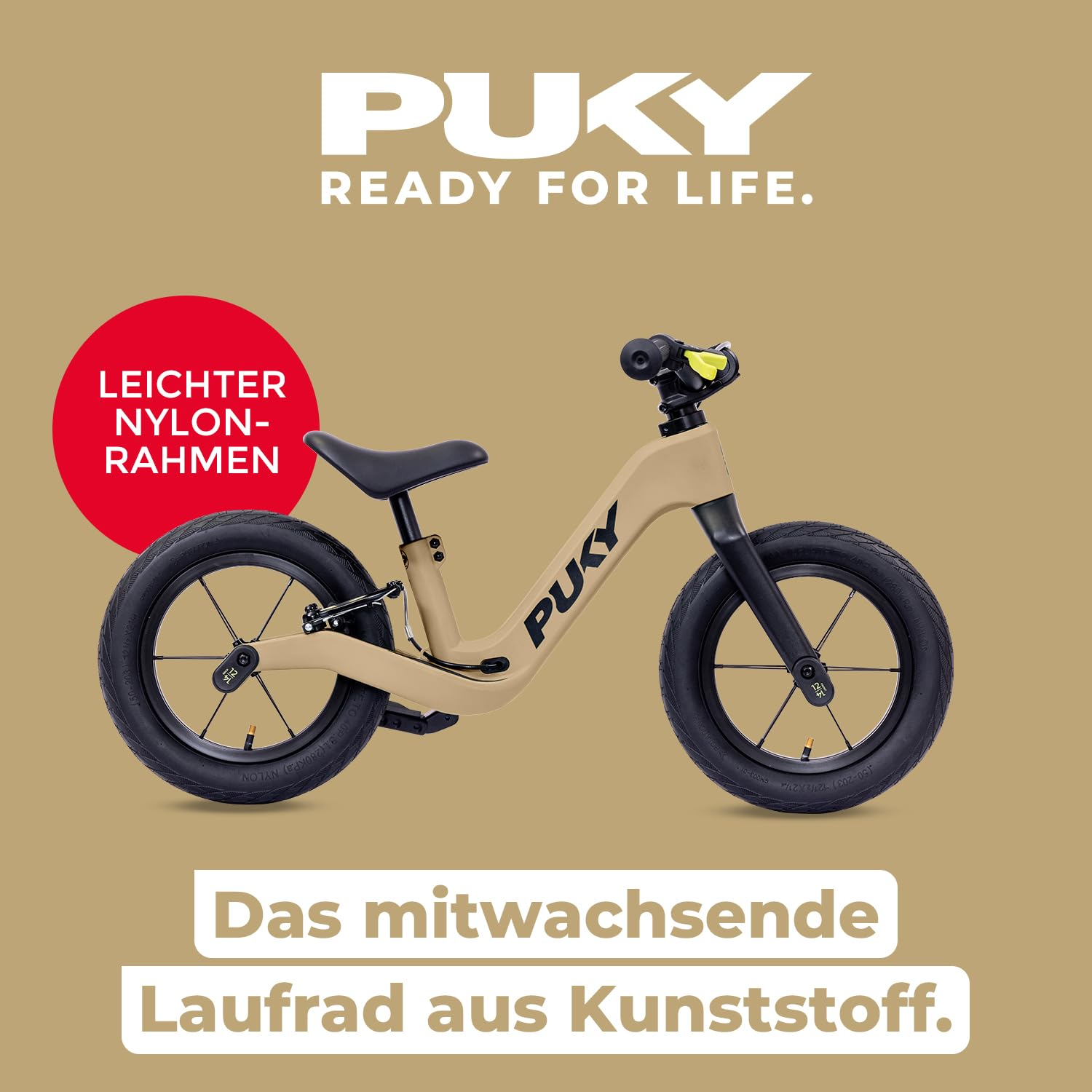 Beiges Puky Laufrad aus Kunststoff mit schwarzem Sattel, Reifen und rotem Hinweisschild vor braunem Hintergrund.