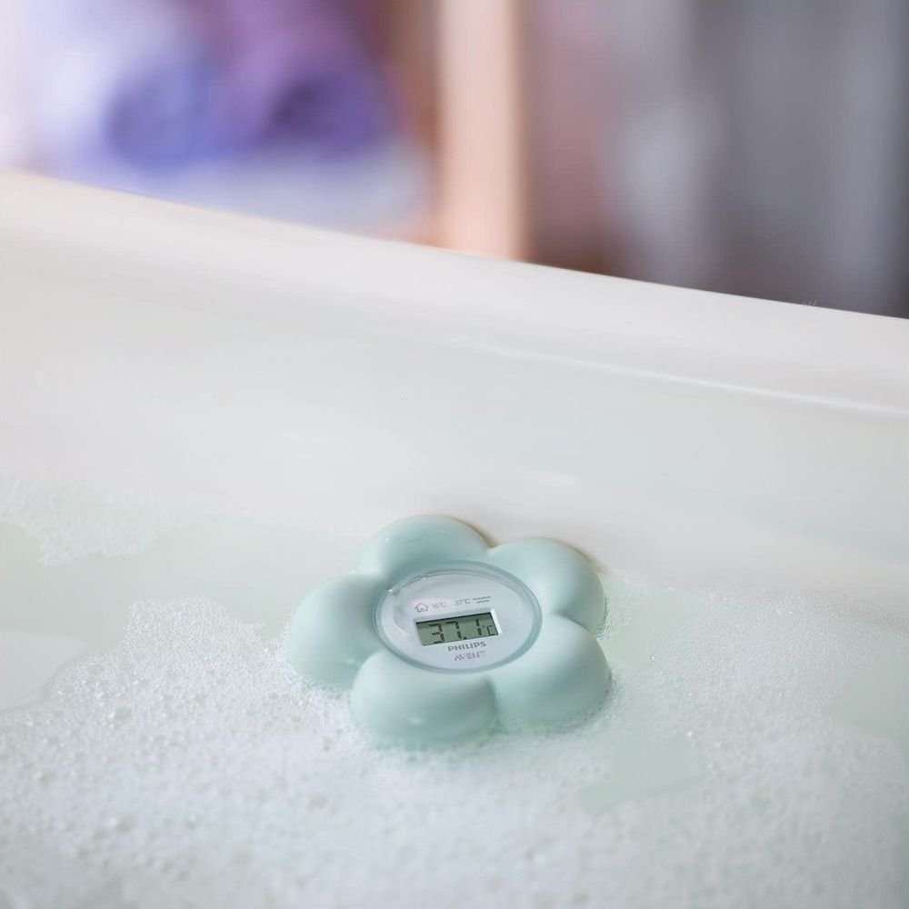 Ein hellblauer, blütenförmiger Philips Avent Badethermometer schwimmt in einem Schaumbad.