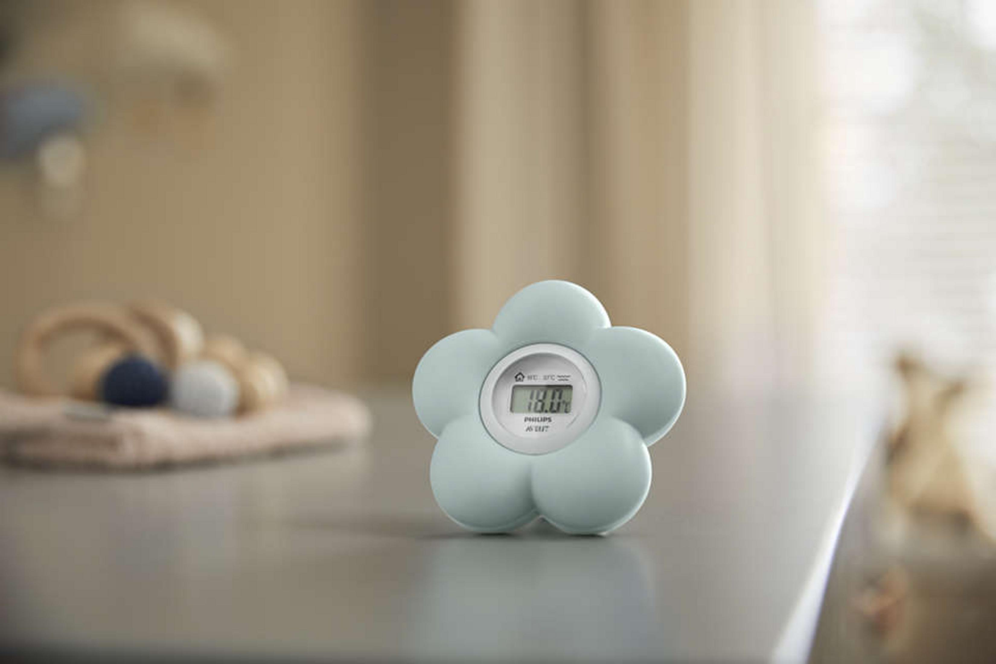 Ein hellblauer, blumenförmiger digitaler Philips Avent Thermometer steht auf einer Tischoberfläche.