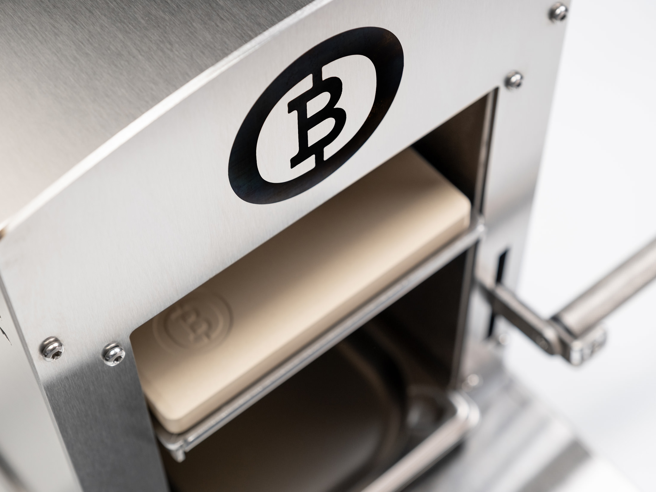 Eine silberne Maschine mit Bitcoin-Logo presst einen hellen Block.