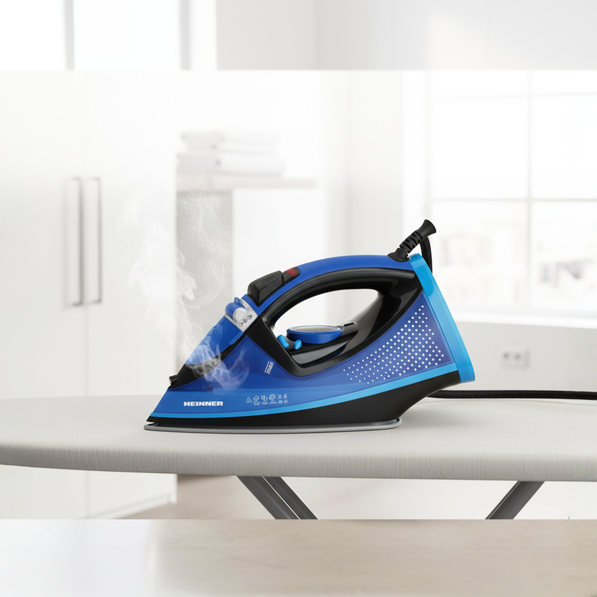 A blue and black steam iron rests on an ironing board, releasing steam.