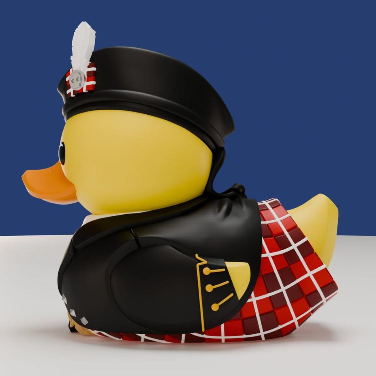 Eine gelbe Gummiente in schottischem Kilt, schwarzer Jacke und Tam-o'-Shanter-Mütze vor blauem Hintergrund.