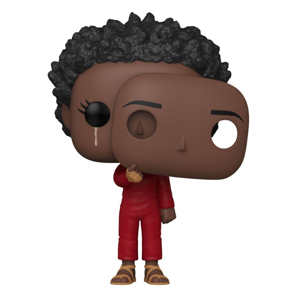 Une figurine en vinyle à la peau foncée en combinaison rouge tenant un masque marron lisse sur son visage.
