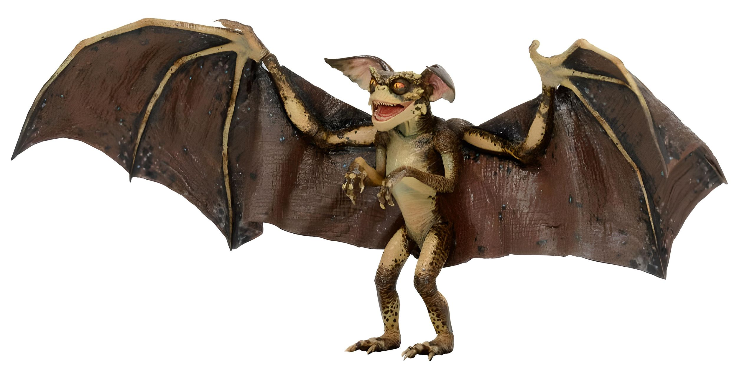 Una figura de Gremlin con grandes alas de murciélago marrones, boca sonriente y ojos amarillos sobre fondo blanco.