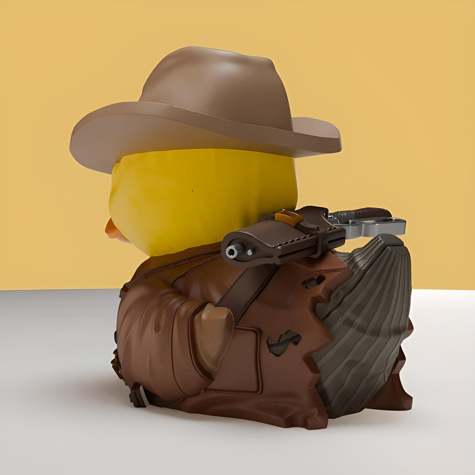 Eine gelbe Gummiente als Abenteurer verkleidet, mit Hut und Jacke sowie einer Pistole auf dem Rücken.