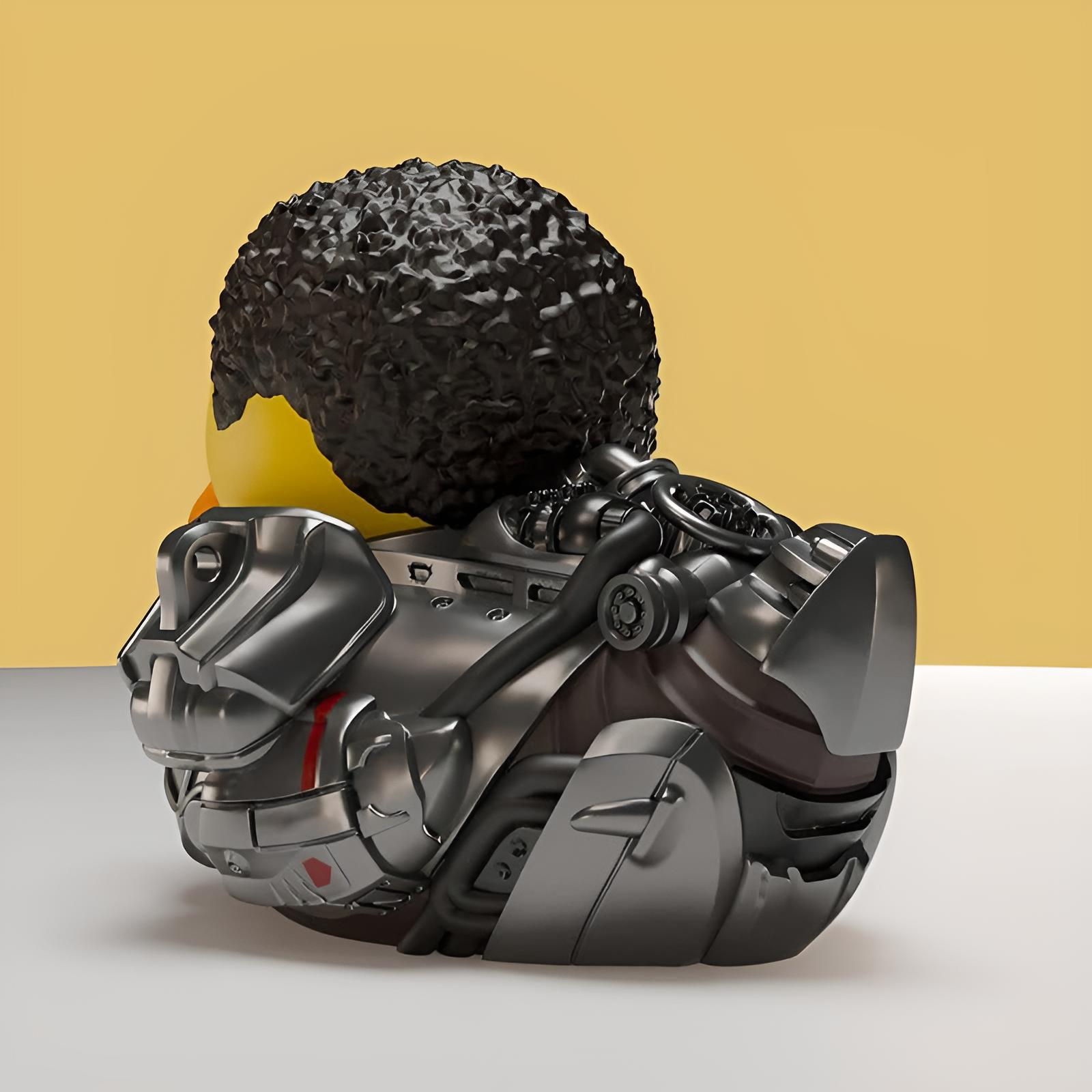 Eine Gummiente mit lockigem schwarzen Haar trägt metallische Sci-Fi-Rüstung auf einem beigen Hintergrund.