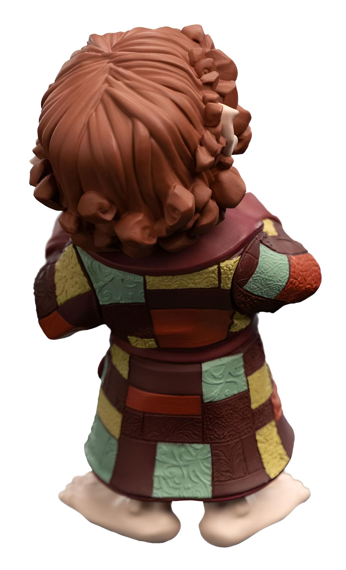 Vista posterior de una pequeña figura con cabello castaño rizado y una túnica estampada colorida sobre fondo blanco.