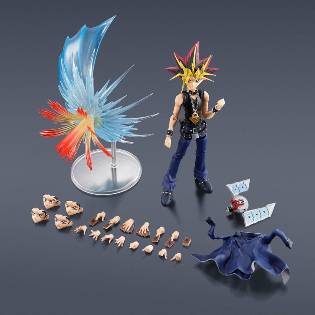 Yami Yugi Actionfigur mit Zubehör wie Gesichtern, Händen, einem blauen Umhang, einem Duell-Disk und einem Effektteil.
