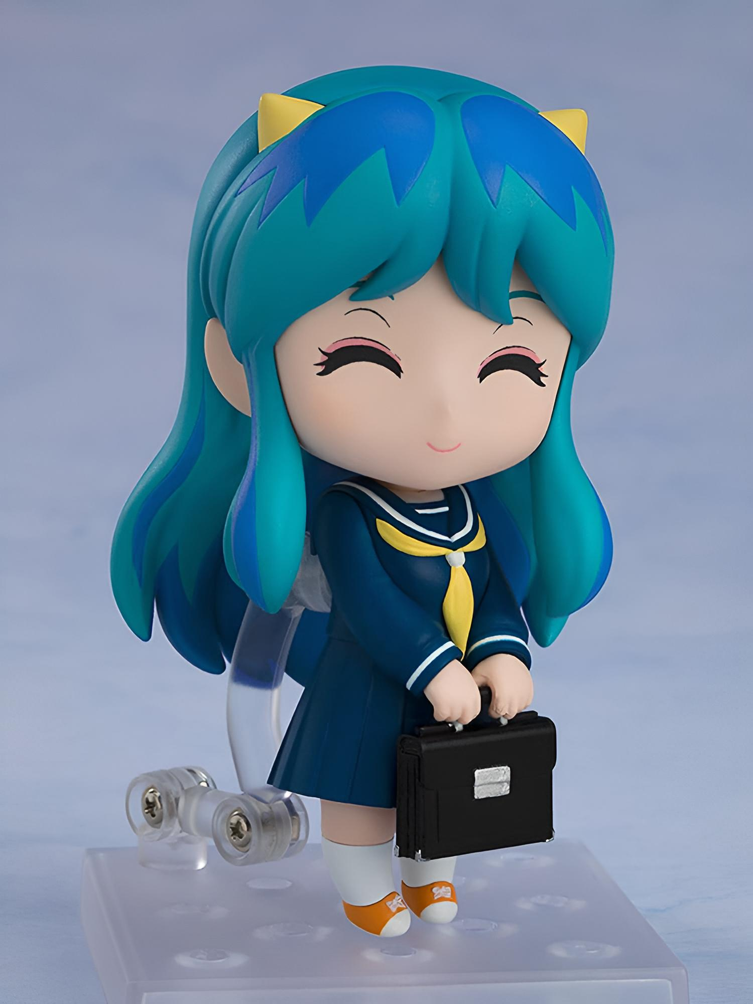 Una linda figura de anime con cabello azul viste uniforme escolar y sostiene un bolso negro.