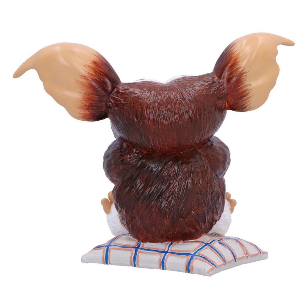Rückansicht einer braunen Gizmo-Figur mit großen Ohren, die auf einem weiß-blau karierten Kissen sitzt.