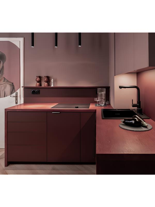 Koyu bordo tonlarında modern, tek renkli mutfak; şık dolaplar, siyah evye ve minimalist sarkıt lambalar içeriyor.