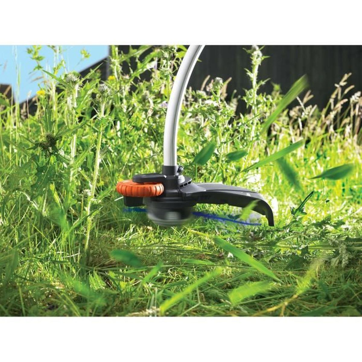 Ein Rasentrimmer schneidet hohes grünes Gras und Unkraut im Garten.