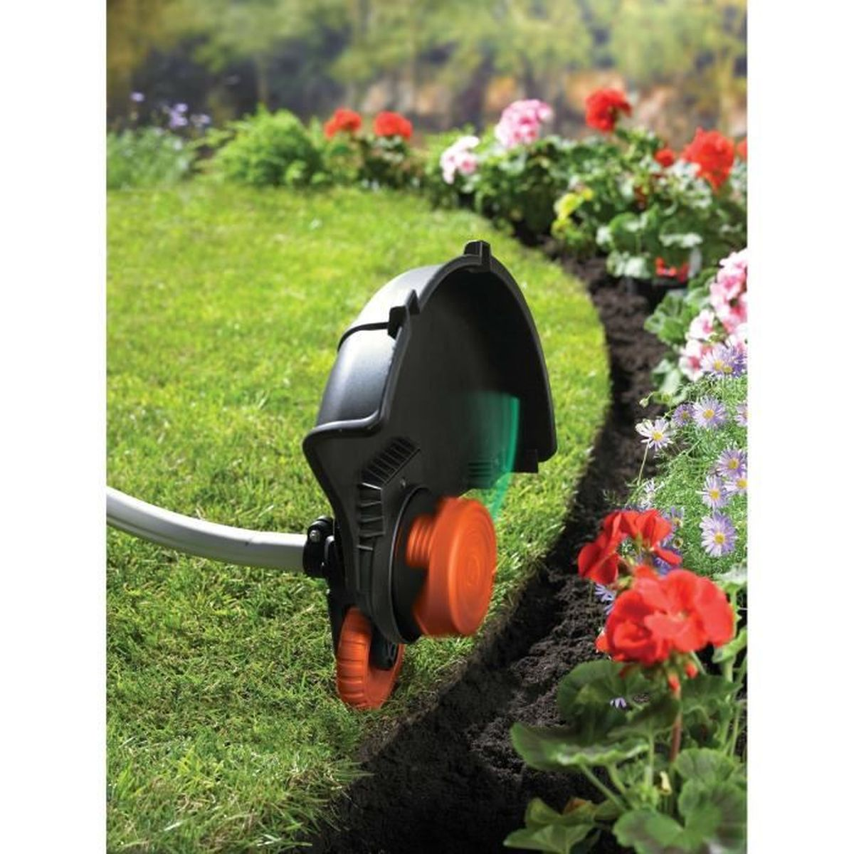 Ein schwarz-oranger Rasenkantenschneider schneidet Gras entlang eines Gartenbeets mit roten und lila Blumen.
